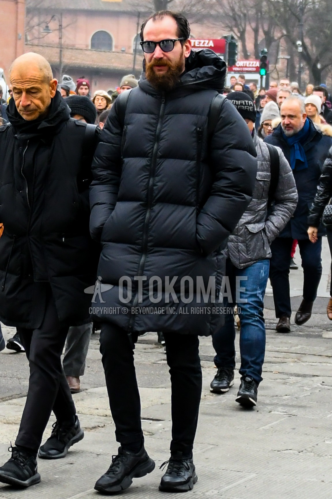 Men's winter outfit with plain sunglasses, black plain down jacket, black plain skinny pants, black low-cut sneakers.