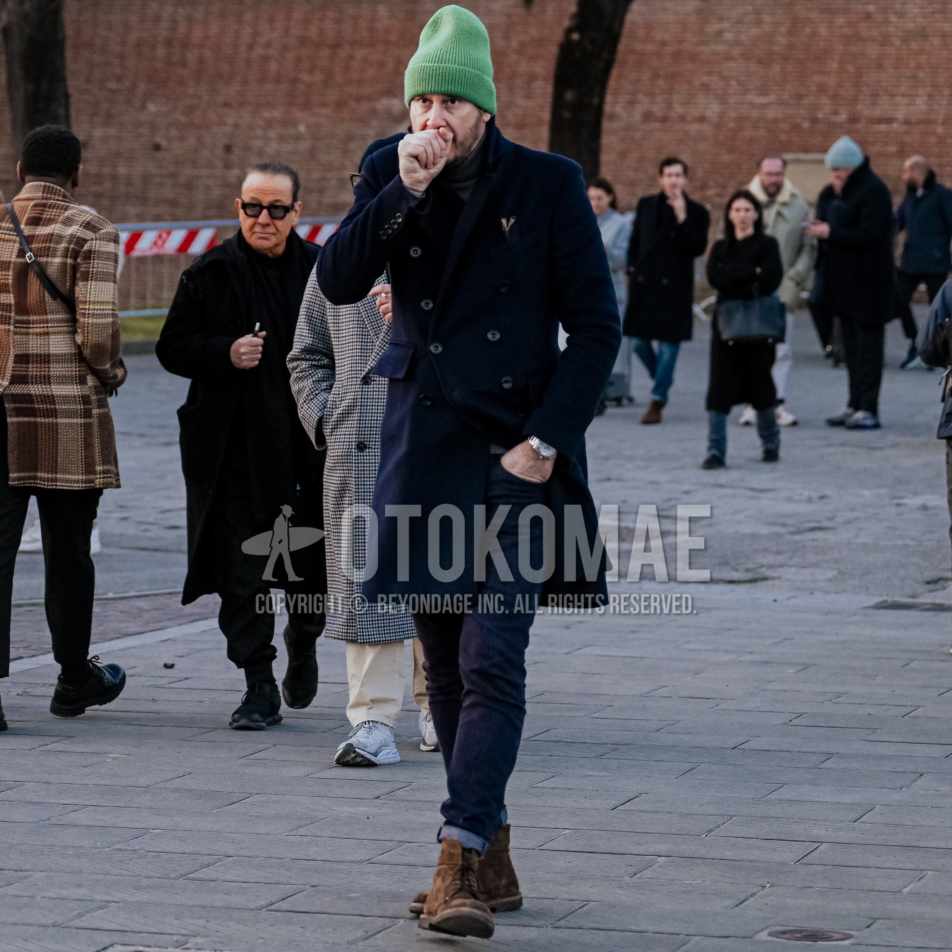 Men's autumn winter outfit with green plain knit cap, navy plain ulster coat, navy bottoms skinny pants, brown work boots.