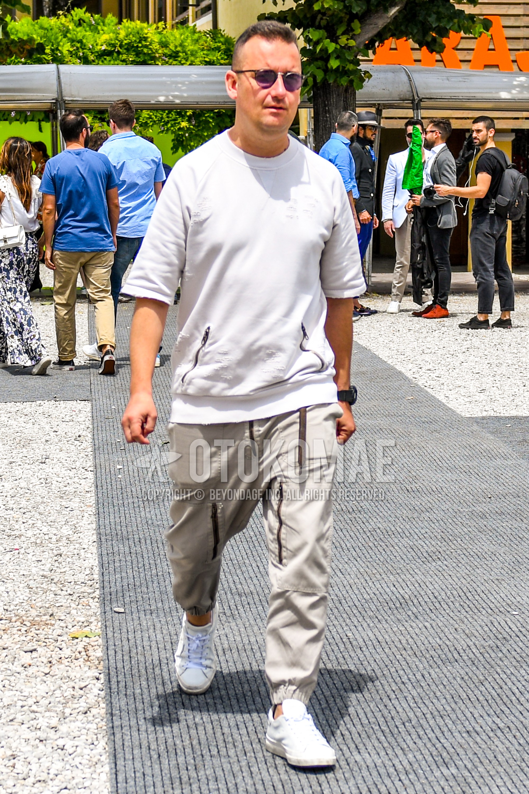 Men's summer outfit with white plain sunglasses, beige plain jogger pants/ribbed pants, white low-cut sneakers.