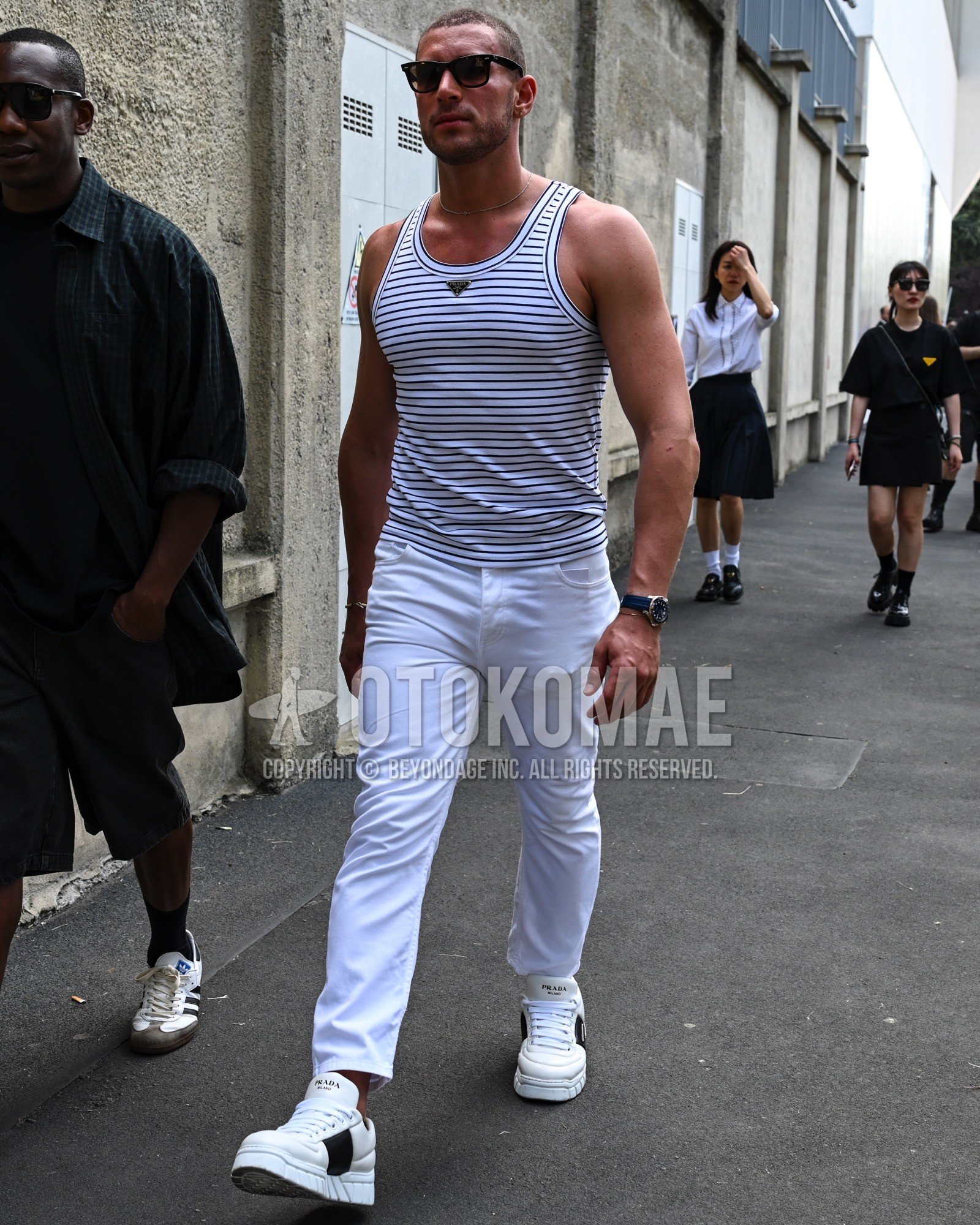 Men's spring summer outfit with white horizontal stripes tank top, white plain denim/jeans, white low-cut sneakers.