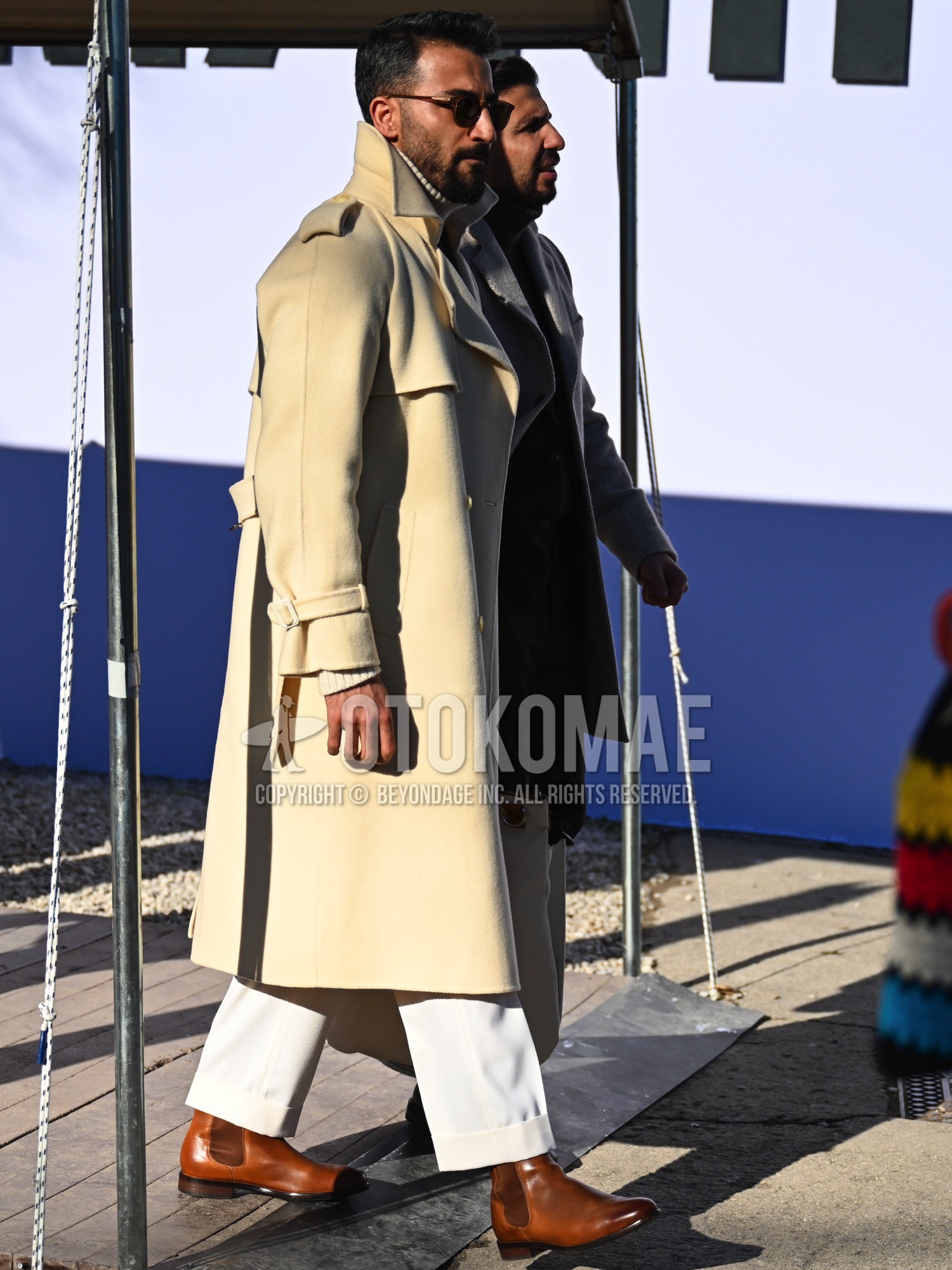 Men's autumn winter outfit with brown tortoiseshell sunglasses, beige plain trench coat, white plain turtleneck knit, white plain slacks, brown side-gore boots.