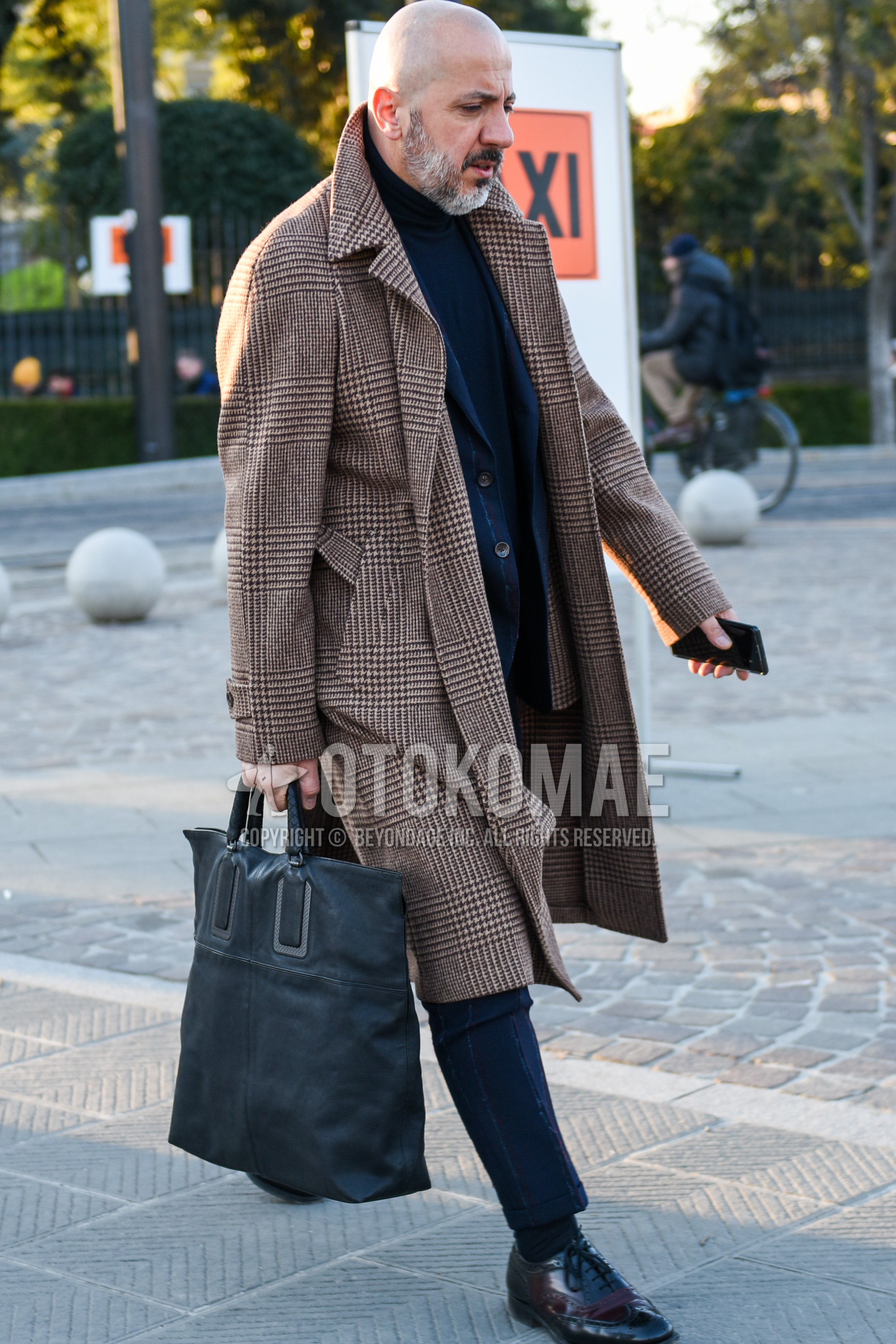 Men's autumn winter outfit with brown check trench coat, navy plain turtleneck knit, brown wing-tip shoes leather shoes, gray plain briefcase/handbag, gray stripes suit.