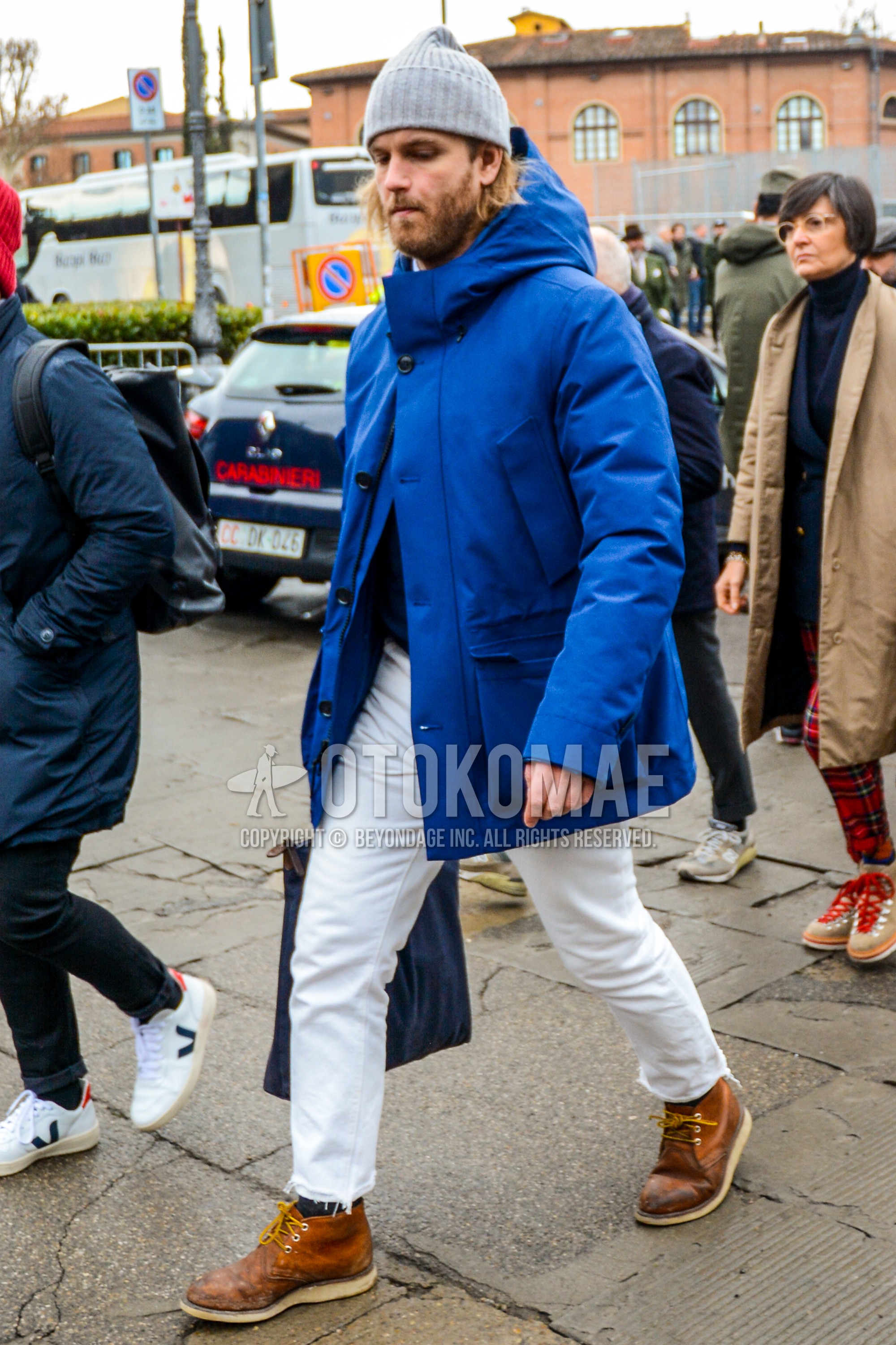 Men's winter outfit with gray plain knit cap, blue plain hooded coat, blue plain down jacket, white plain denim/jeans, dark gray plain socks, brown chukka boots.