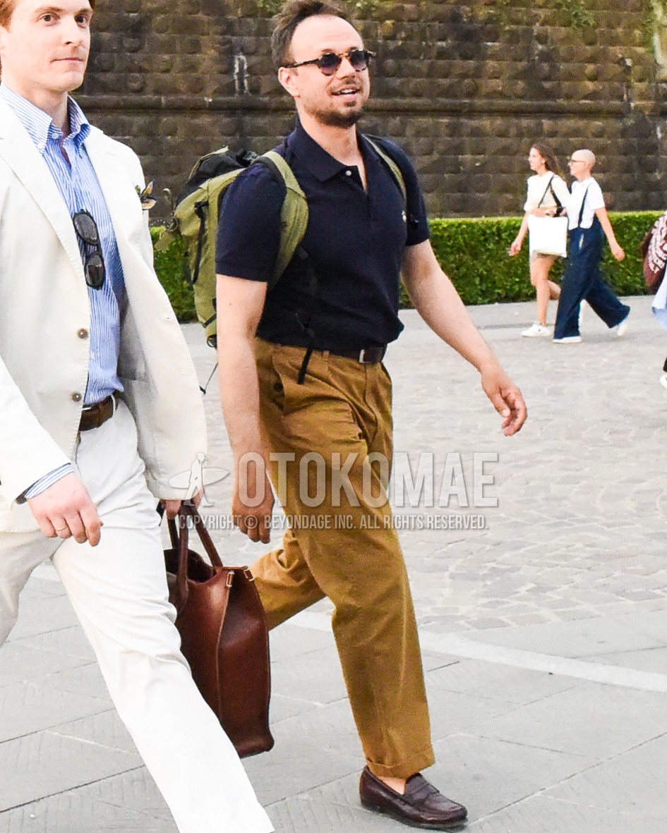 Men's spring summer outfit with brown tortoiseshell sunglasses, navy plain polo shirt, brown plain leather belt, brown plain chinos, brown coin loafers leather shoes, olive green plain backpack.
