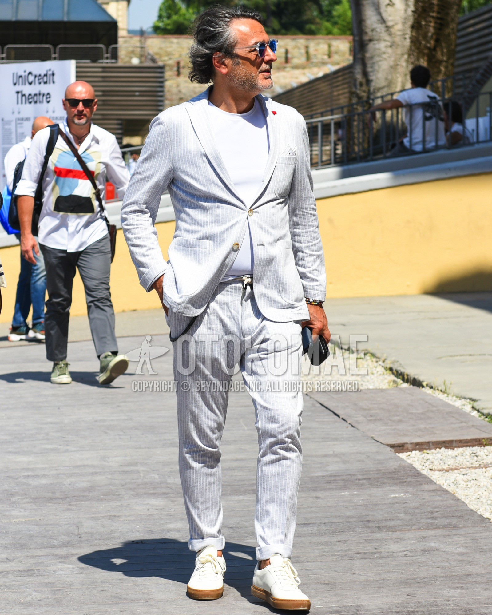 Men's spring summer outfit with clear plain sunglasses, white plain t-shirt, white low-cut sneakers, gray stripes suit.
