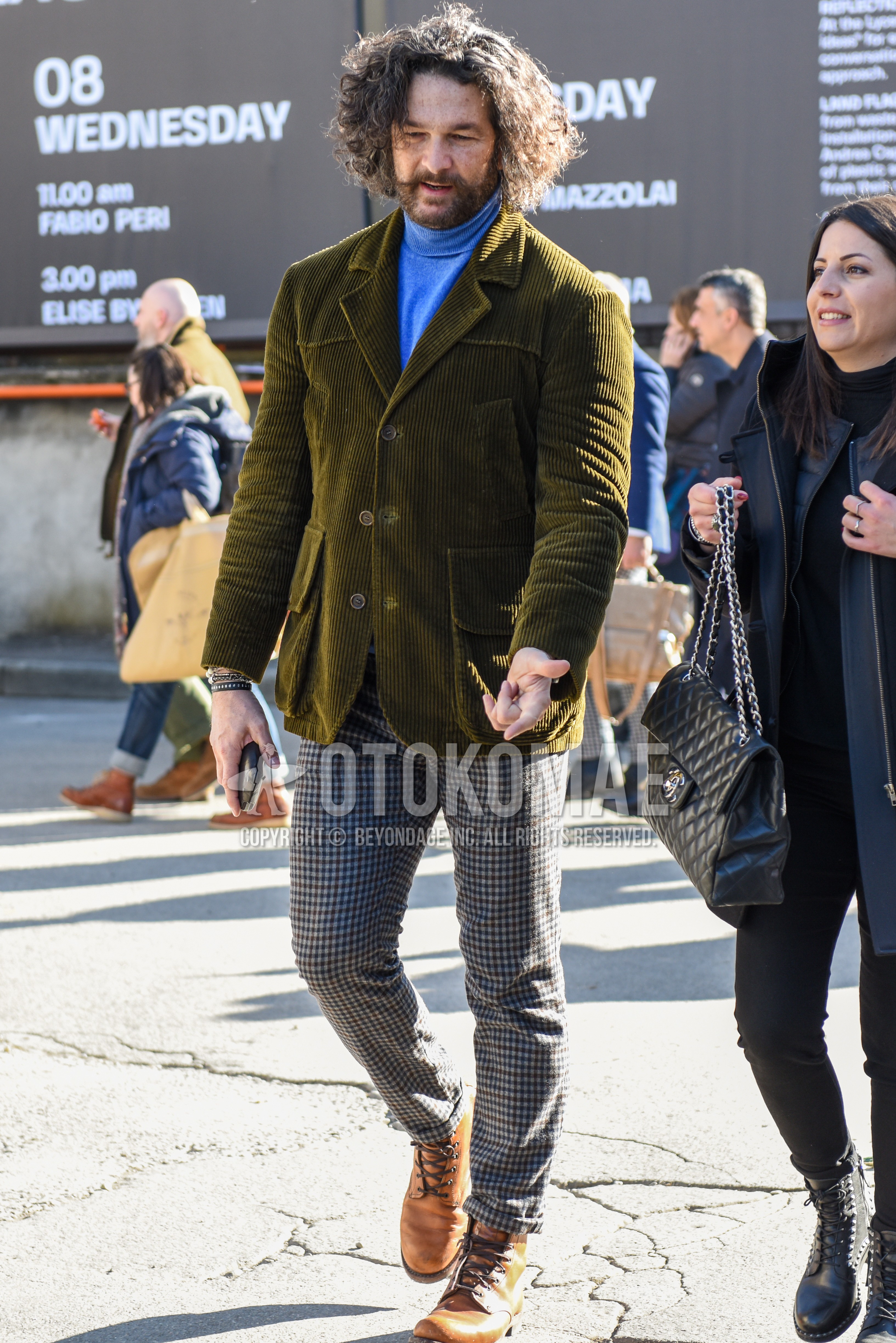 Men's autumn winter outfit with olive green plain tailored jacket, blue light blue plain turtleneck knit, gray check slacks, brown work boots.