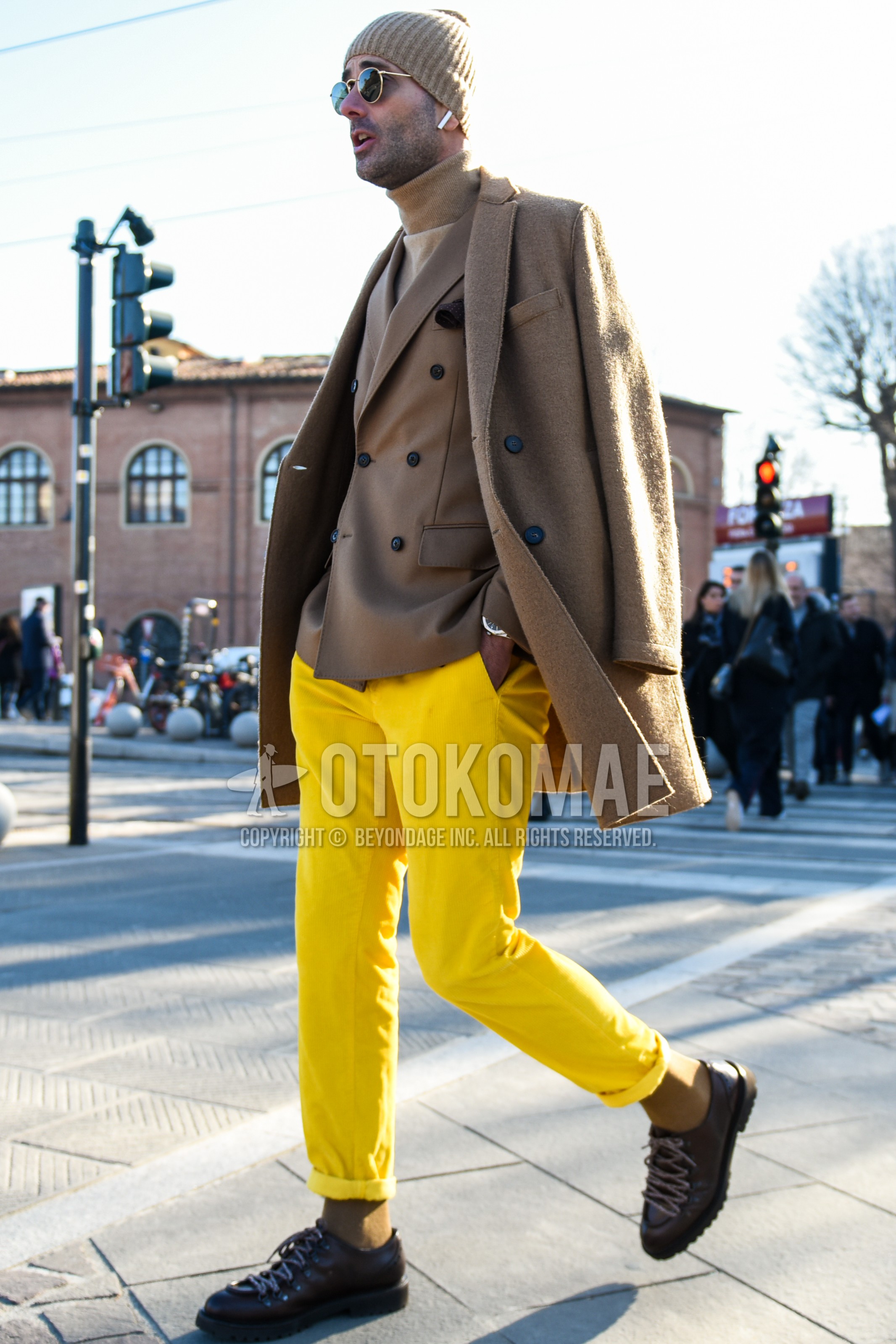 Men's autumn winter outfit with gold plain sunglasses, beige plain chester coat, beige plain tailored jacket, beige plain turtleneck knit, yellow plain cotton pants, brown  leather shoes.