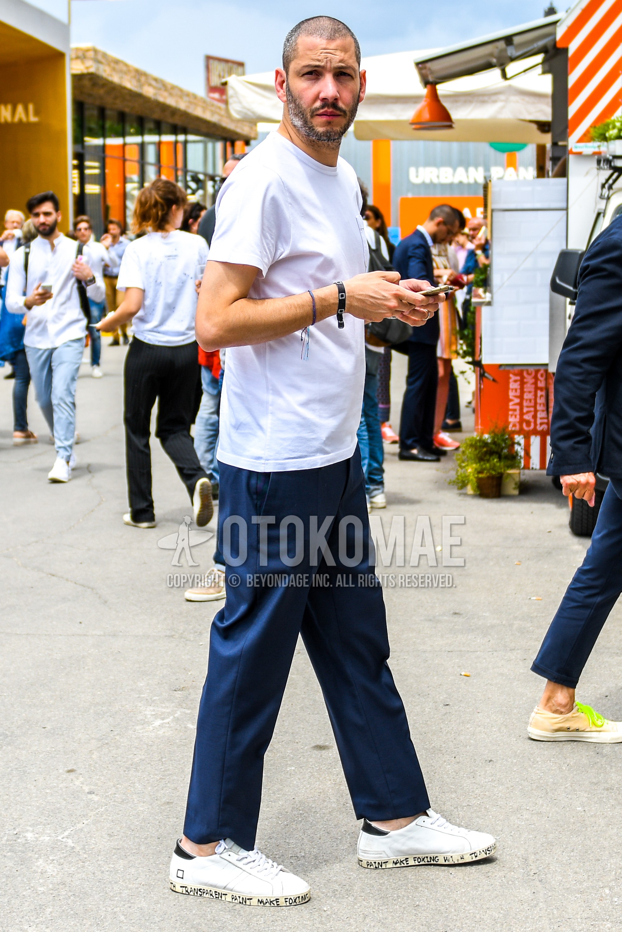 Men's summer outfit with white plain t-shirt, navy plain ankle pants, white low-cut sneakers.