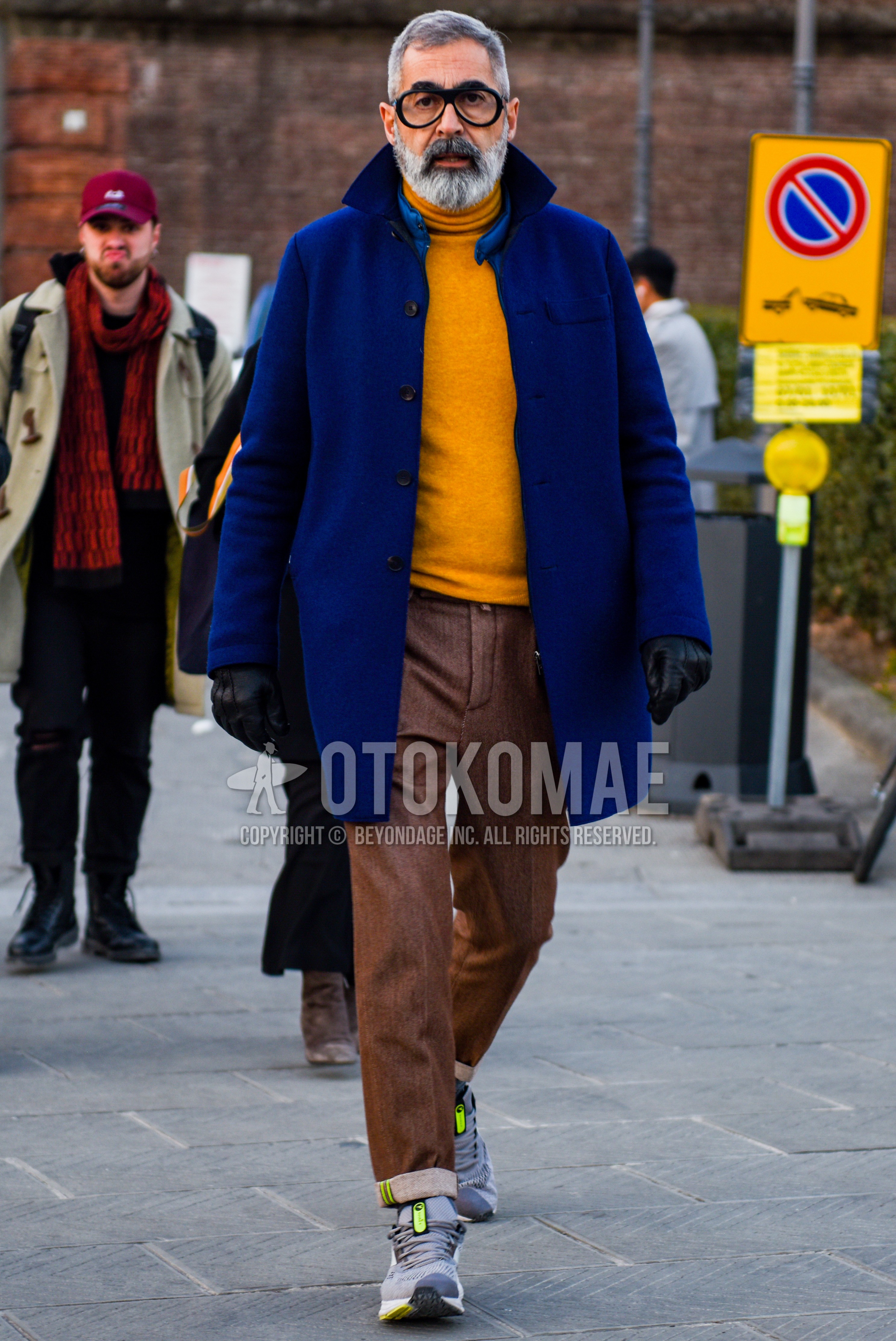 Men's autumn winter outfit with black plain glasses, blue plain stenkarrer coat, yellow plain turtleneck knit, brown plain slacks, gray low-cut sneakers.