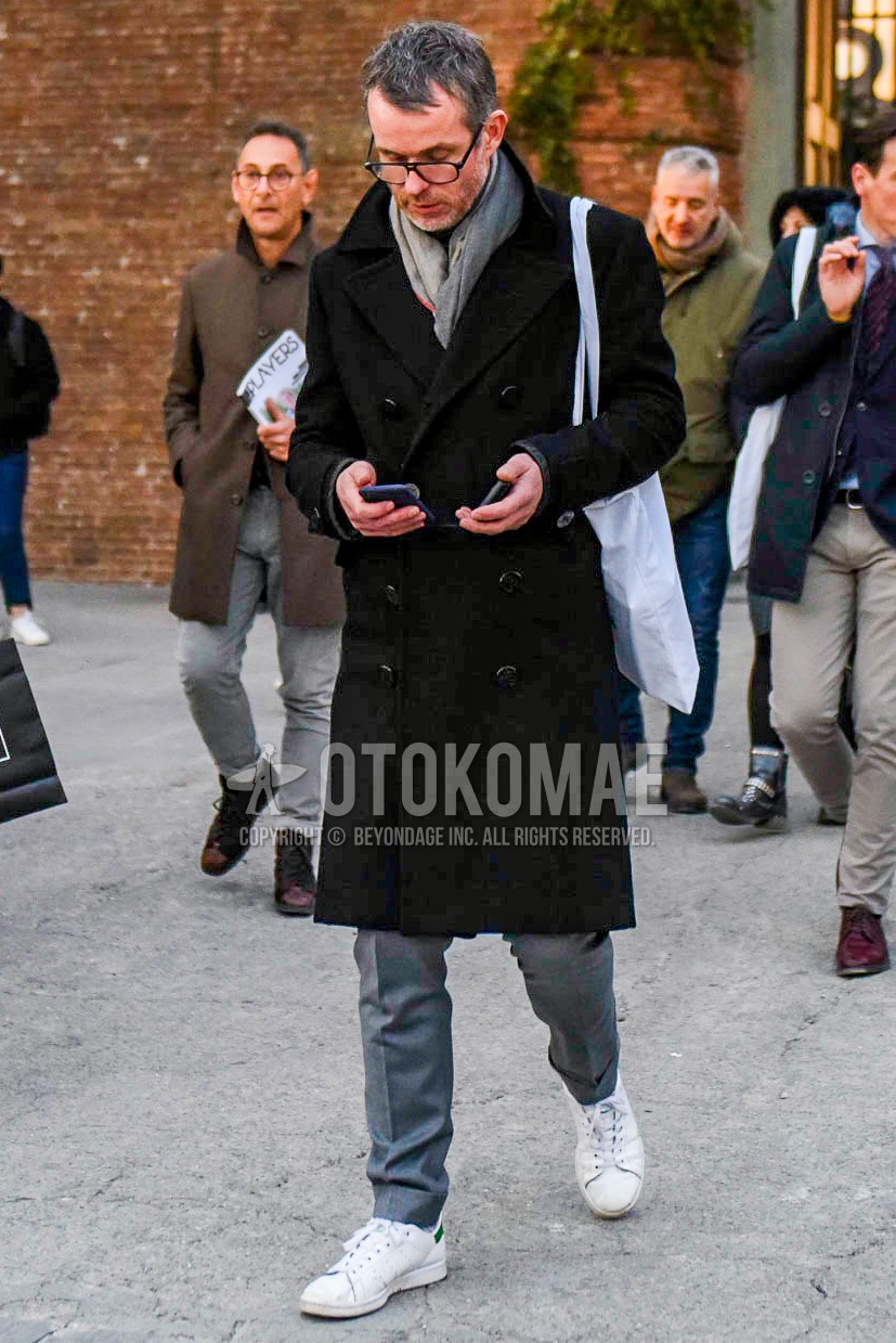 Men's autumn winter outfit with black plain glasses, gray plain scarf, black plain ulster coat, gray plain slacks, white low-cut sneakers, white plain tote bag.
