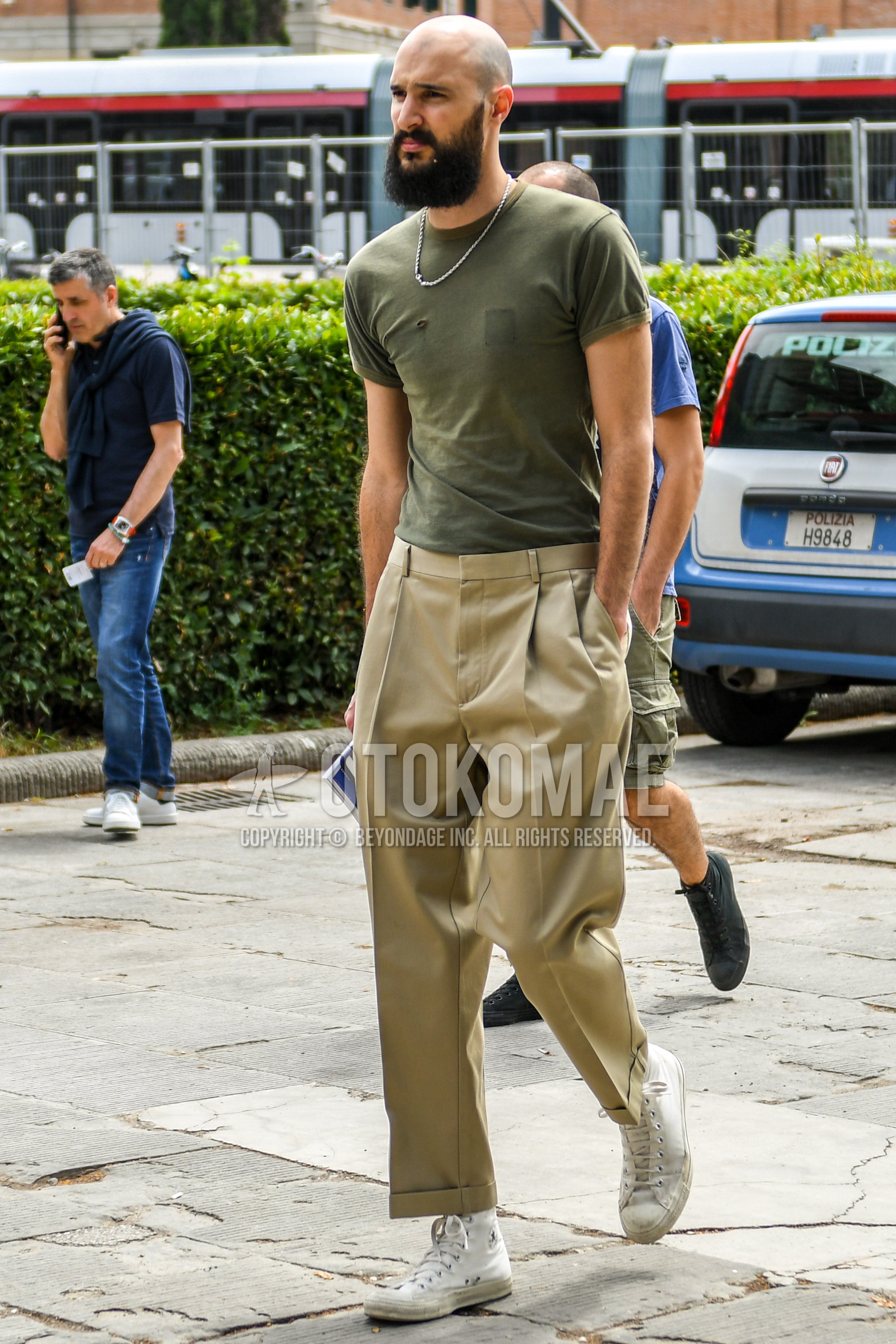Men's spring summer outfit with olive green plain t-shirt, beige plain chinos, beige plain beltless pants, white high-cut sneakers.
