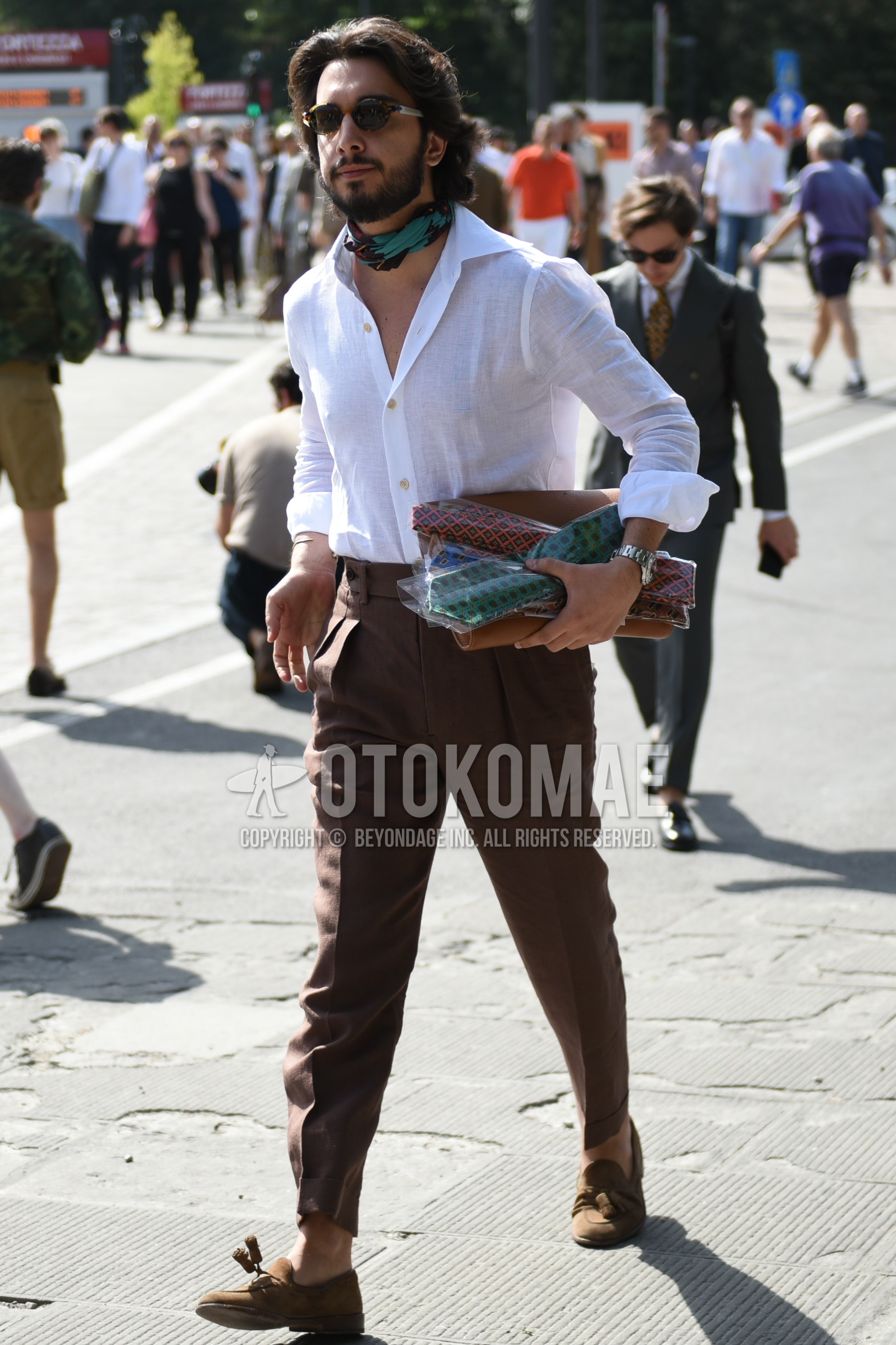 Men's spring summer outfit with brown tortoiseshell sunglasses, green plain scarf, white plain shirt, brown plain slacks, brown tassel loafers leather shoes.