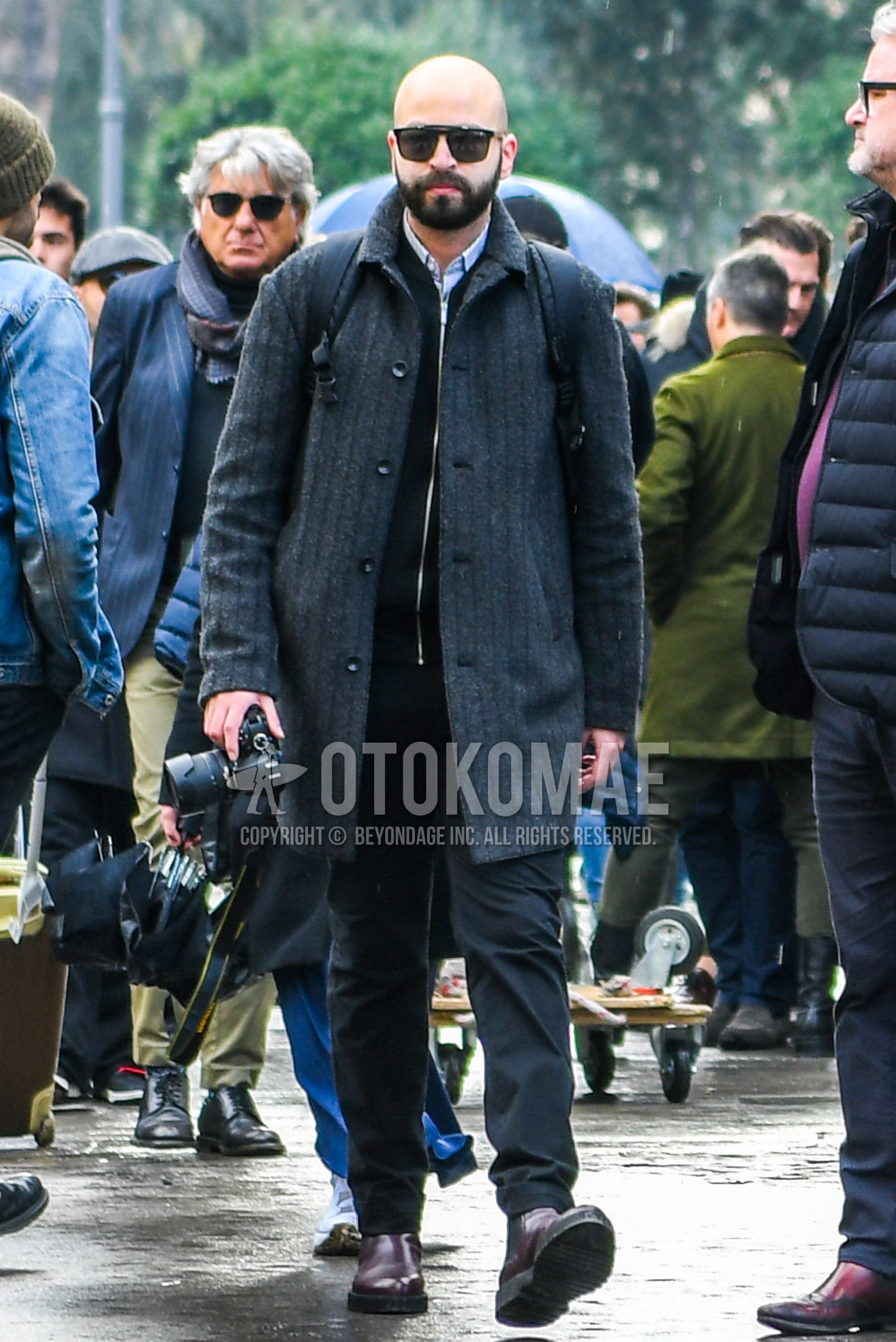 Men's winter outfit with black plain sunglasses, dark gray stripes stenkarrer coat, light blue plain shirt, black plain cardigan, black plain cotton pants, brown side-gore boots.
