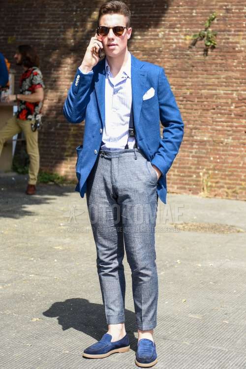 黒無地のサングラス、ブルー無地のテーラードジャケット、水色無地のシャツ、ネイビー無地のサスペンダー、グレー無地のベルトレスパンツ、ブルーローファーの革靴を合わせた春夏秋のメンズコーデ・着こなし。