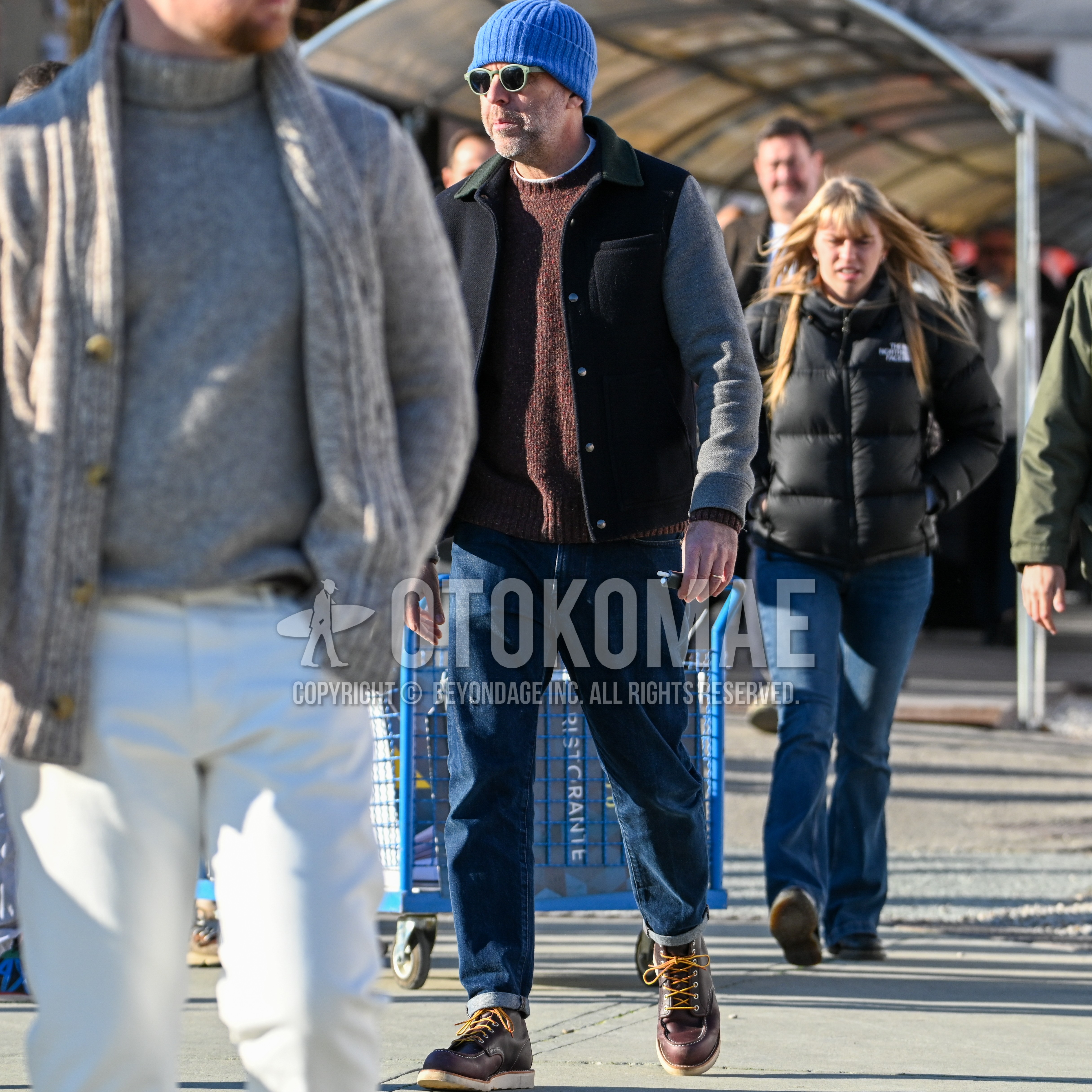 Men's autumn winter outfit with light blue plain knit cap, green plain sunglasses, gray dark gray outerwear shirt jacket, brown plain sweater, plain denim/jeans, brown work boots.