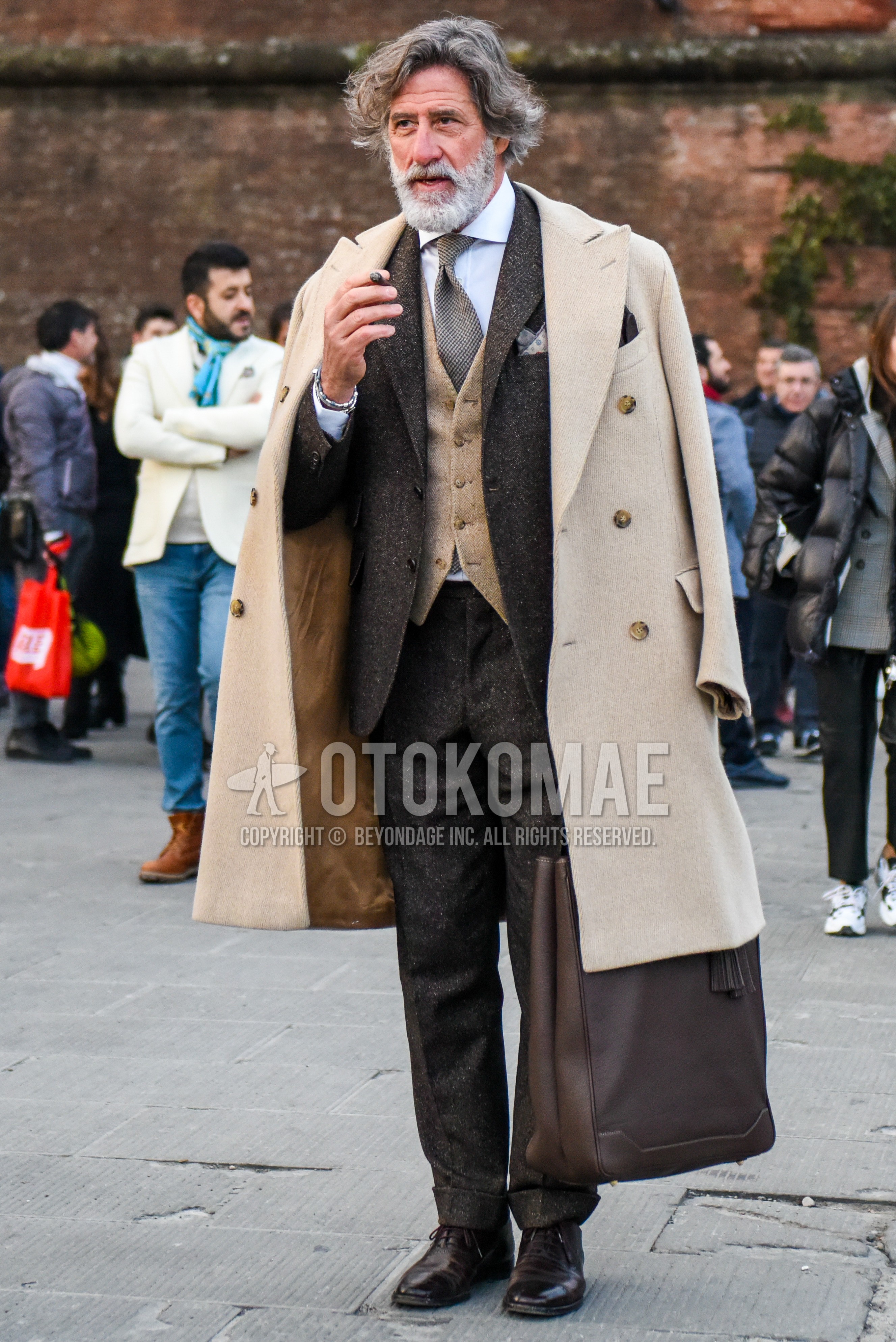 Men's winter outfit with beige plain chester coat, beige plain gilet, white plain shirt, brown straight-tip shoes leather shoes, brown plain tote bag, brown plain suit, brown necktie necktie.