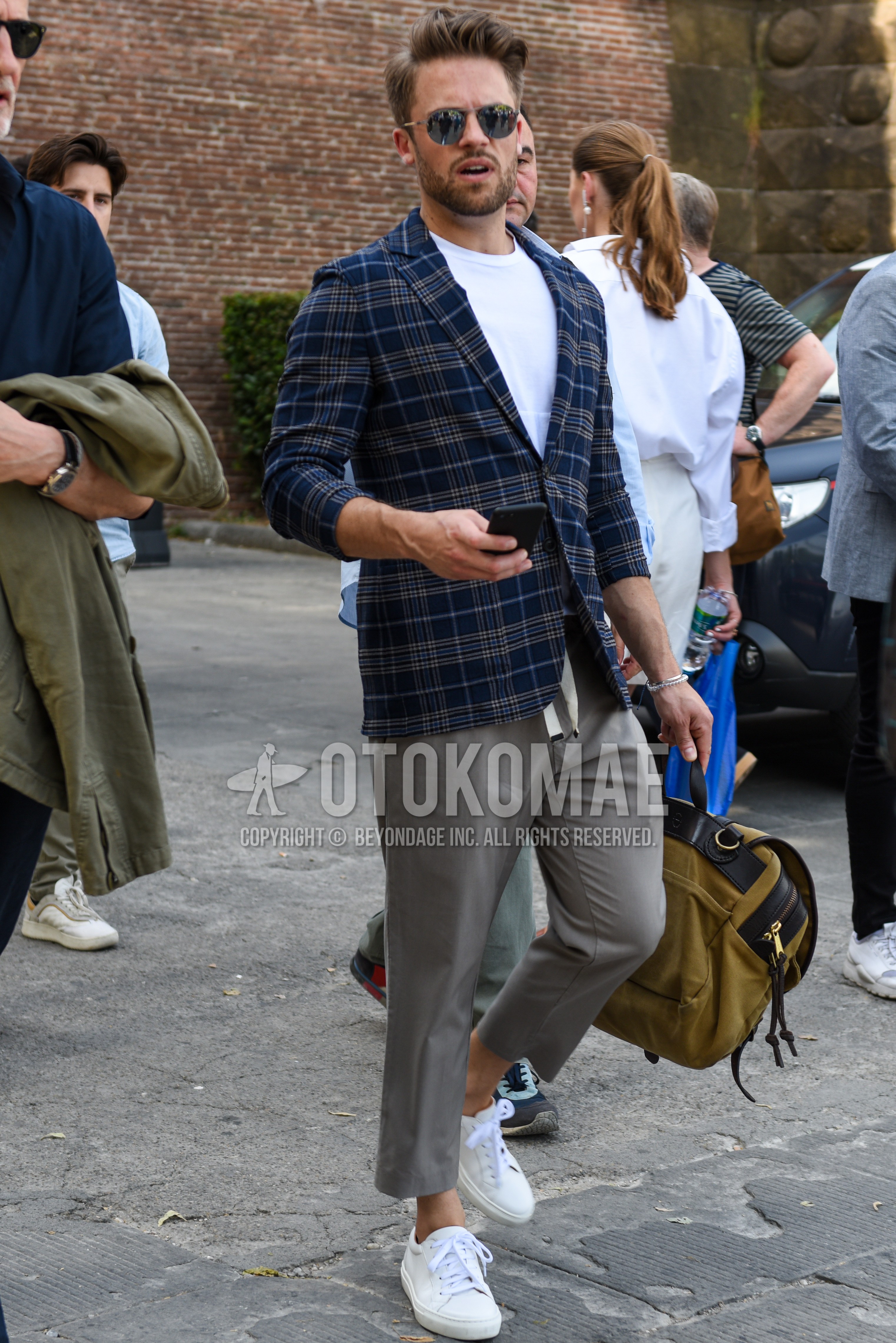 Men's spring summer autumn outfit with silver plain sunglasses, navy check tailored jacket, white plain t-shirt, gray plain easy pants, white low-cut sneakers.