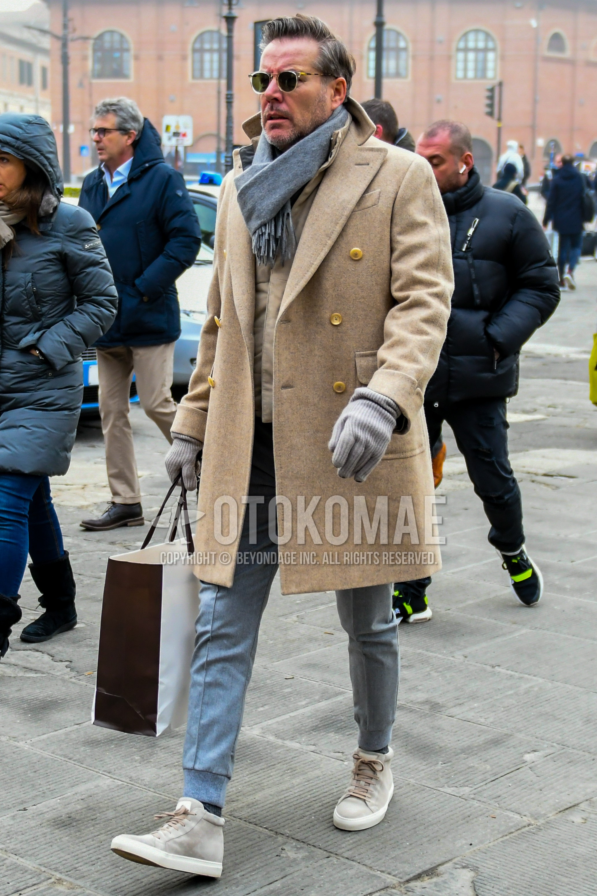 Men's winter outfit with plain sunglasses, beige plain chester coat, beige plain inner down, gray plain sweatpants, beige high-cut sneakers.