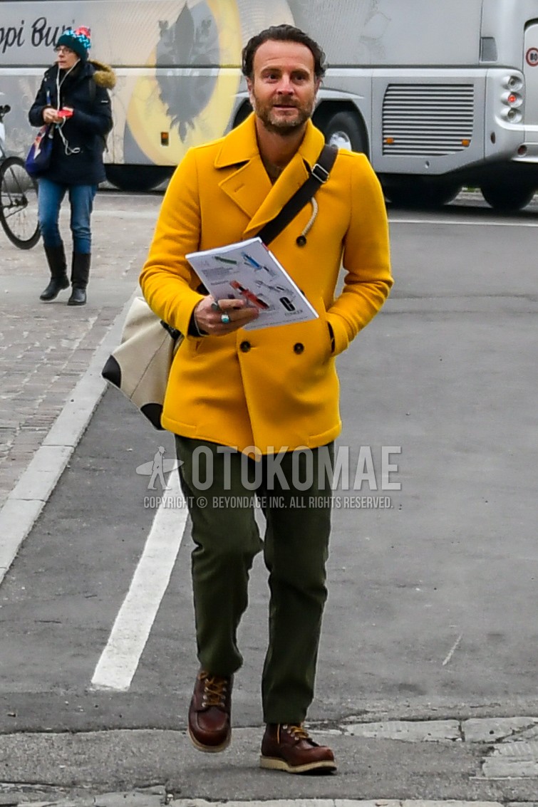 Men's winter outfit with yellow plain p coat, olive green plain ankle pants, brown work boots.