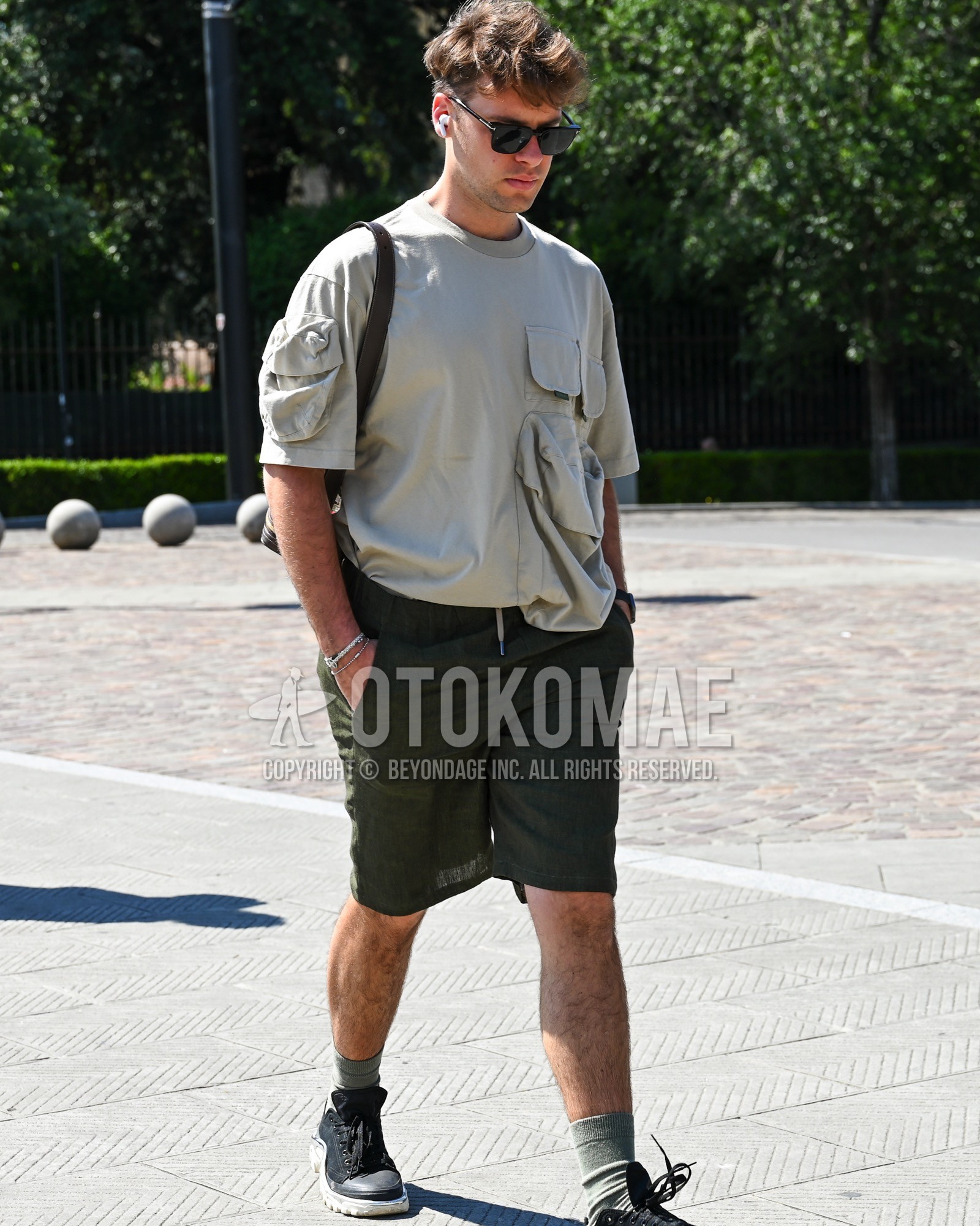 Men's spring summer outfit with black plain sunglasses, gray plain t-shirt, olive green plain short pants, gray plain socks, navy low-cut sneakers.