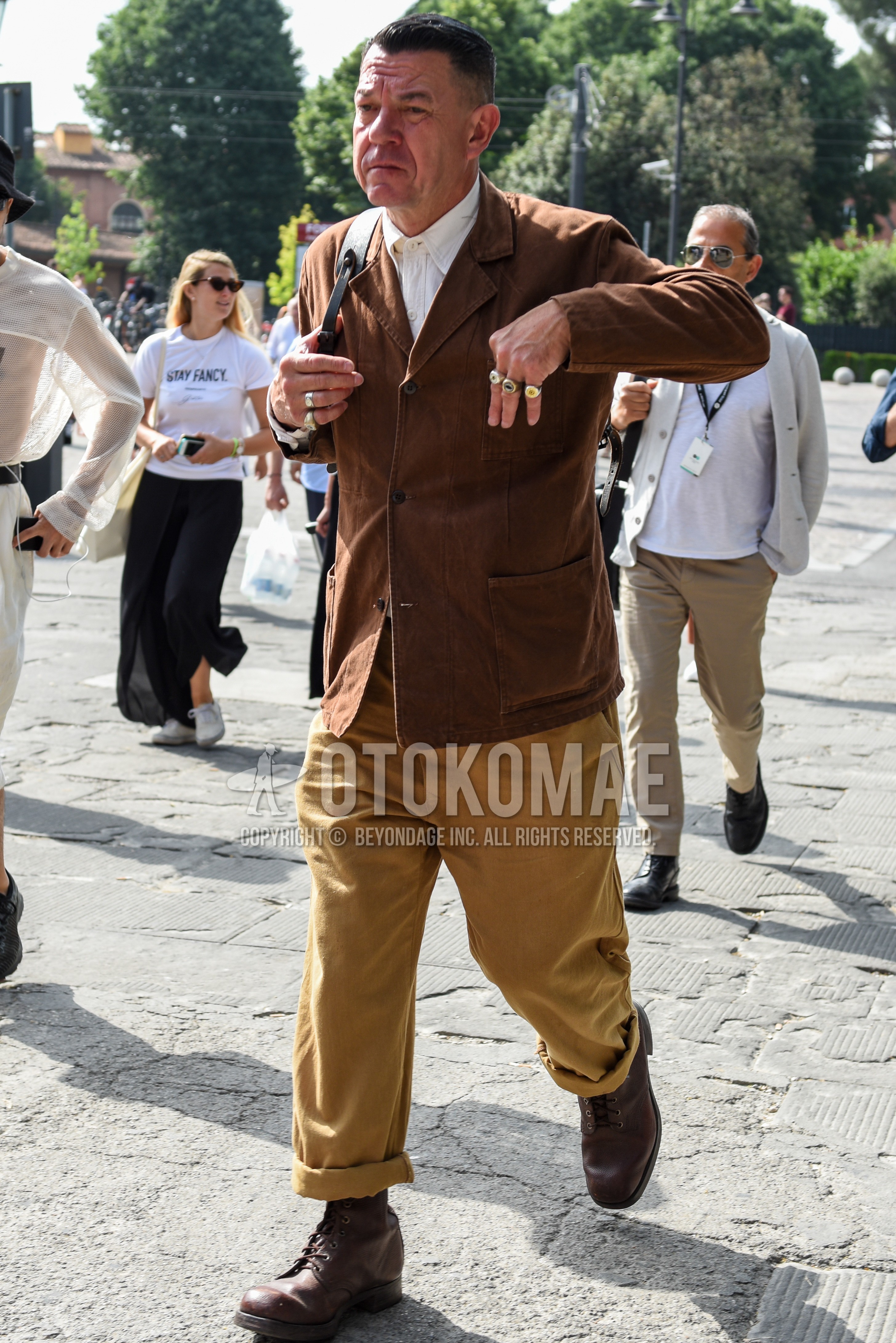 Men's spring autumn outfit with brown plain tailored jacket, white plain shirt, beige plain chinos, brown  boots.