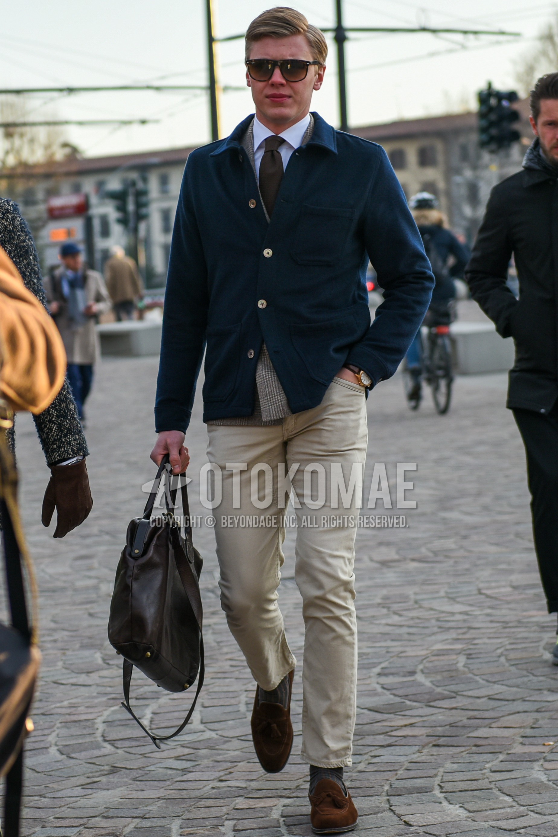 Men's autumn winter outfit with brown tortoiseshell sunglasses, navy plain shirt jacket, gray check tailored jacket, white plain shirt, beige plain chinos, gray plain socks, brown tassel loafers leather shoes, brown plain briefcase/handbag, gray plain necktie.