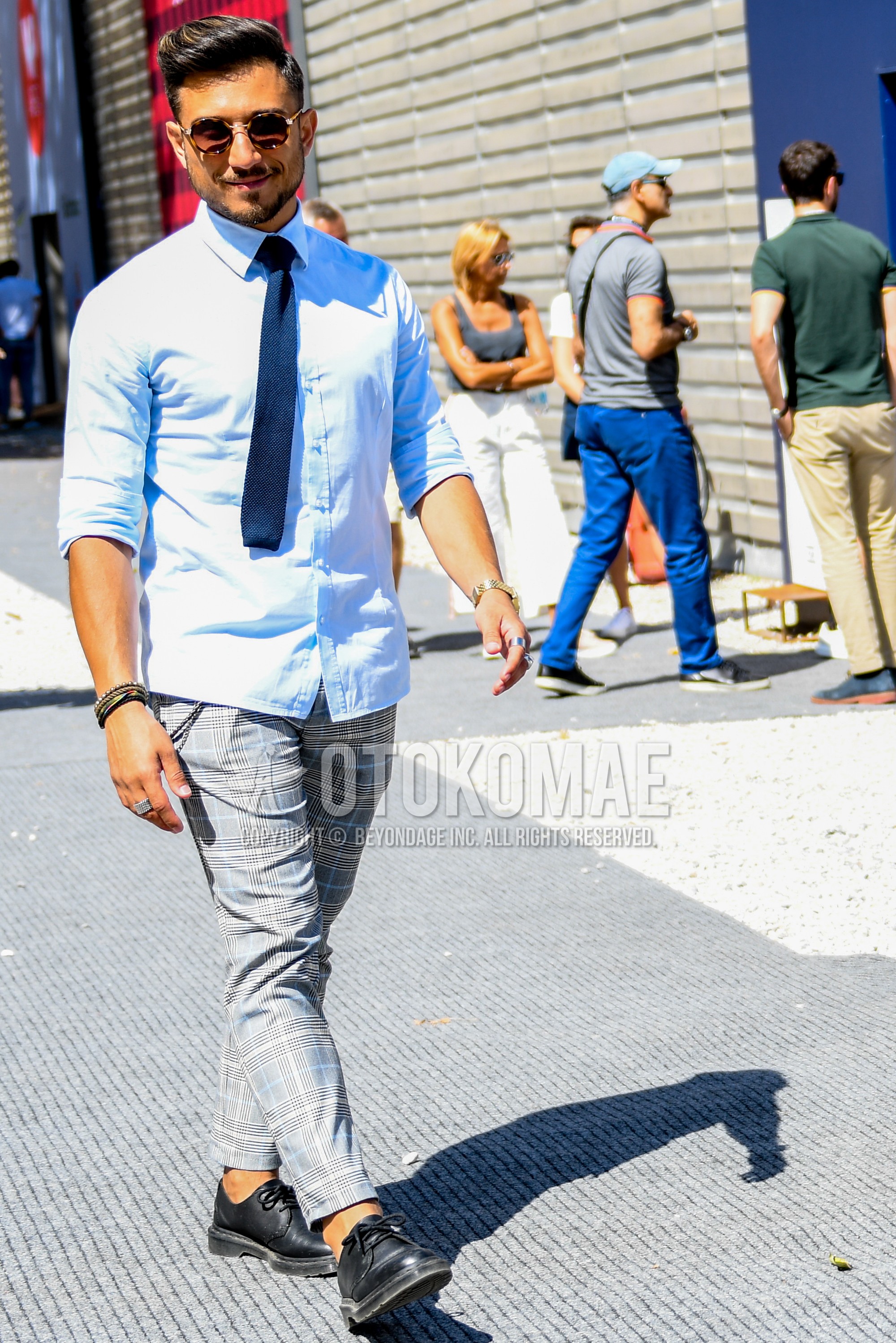 Men's spring summer autumn outfit with plain sunglasses, light blue plain shirt, gray check slacks, black plain toe leather shoes.