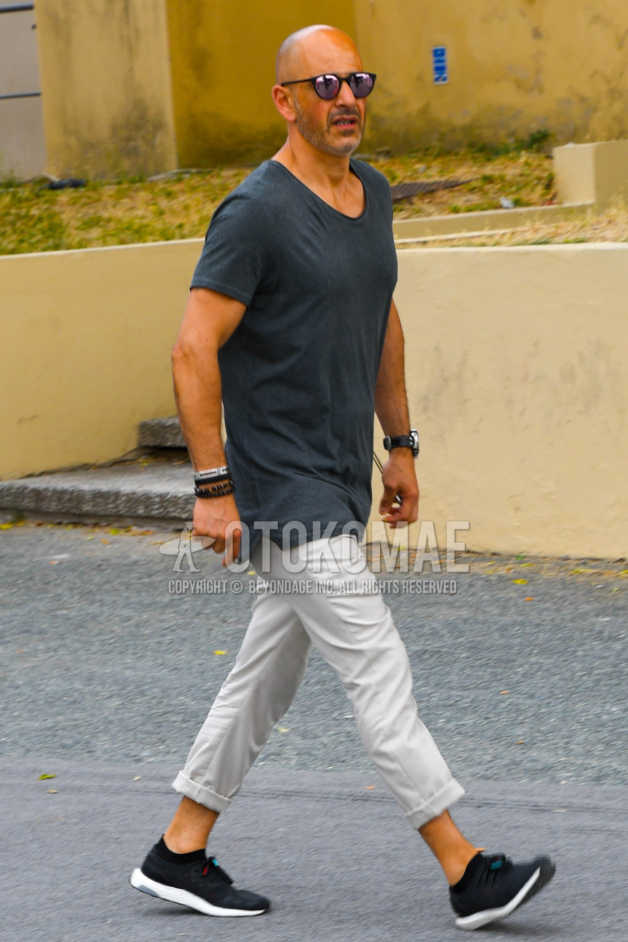 Men's summer outfit with plain sunglasses, dark gray plain t-shirt, white plain cotton pants, navy low-cut sneakers.
