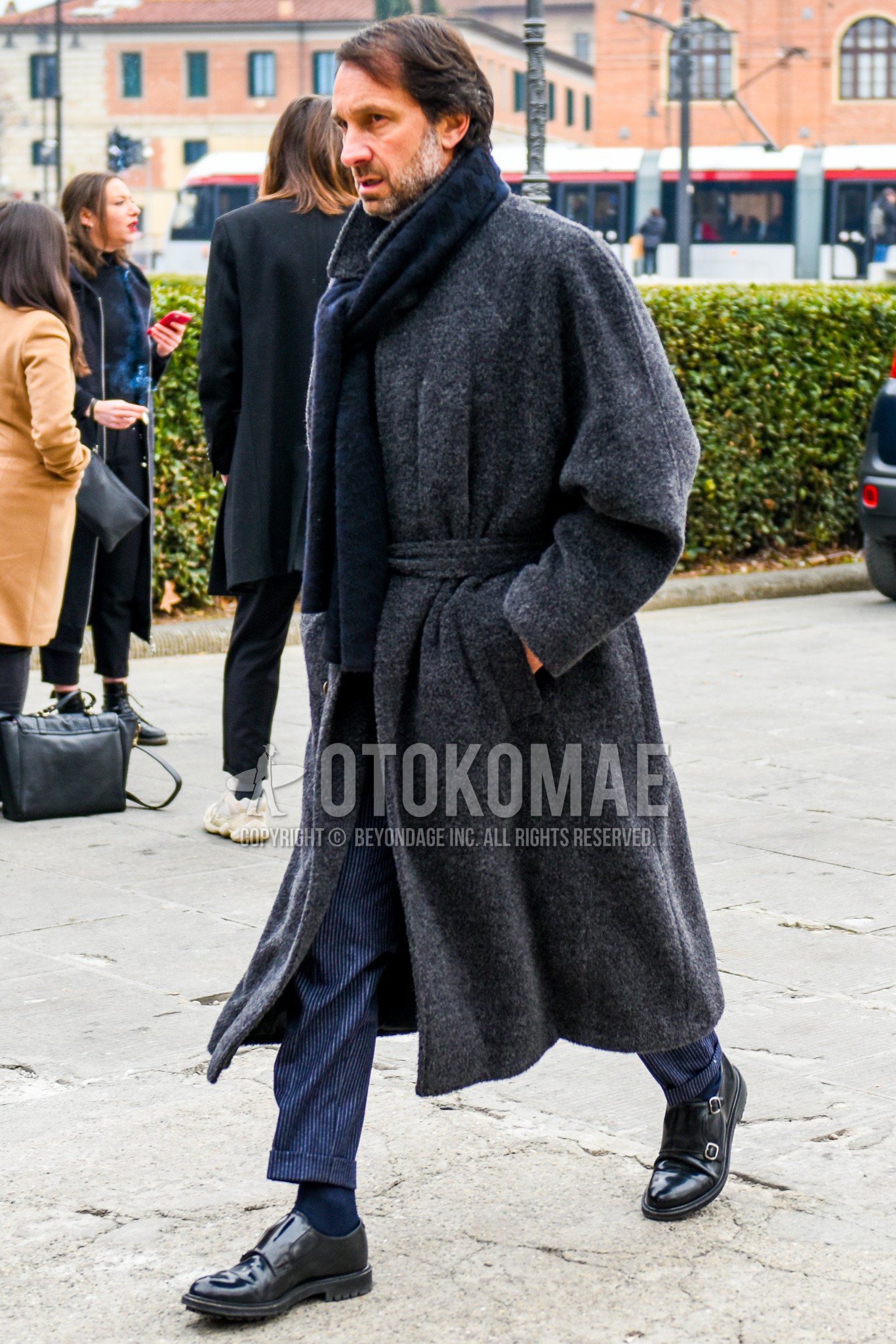 Men's winter outfit with navy plain scarf, dark gray plain belted coat, navy plain slacks, navy plain socks, black monk shoes leather shoes.