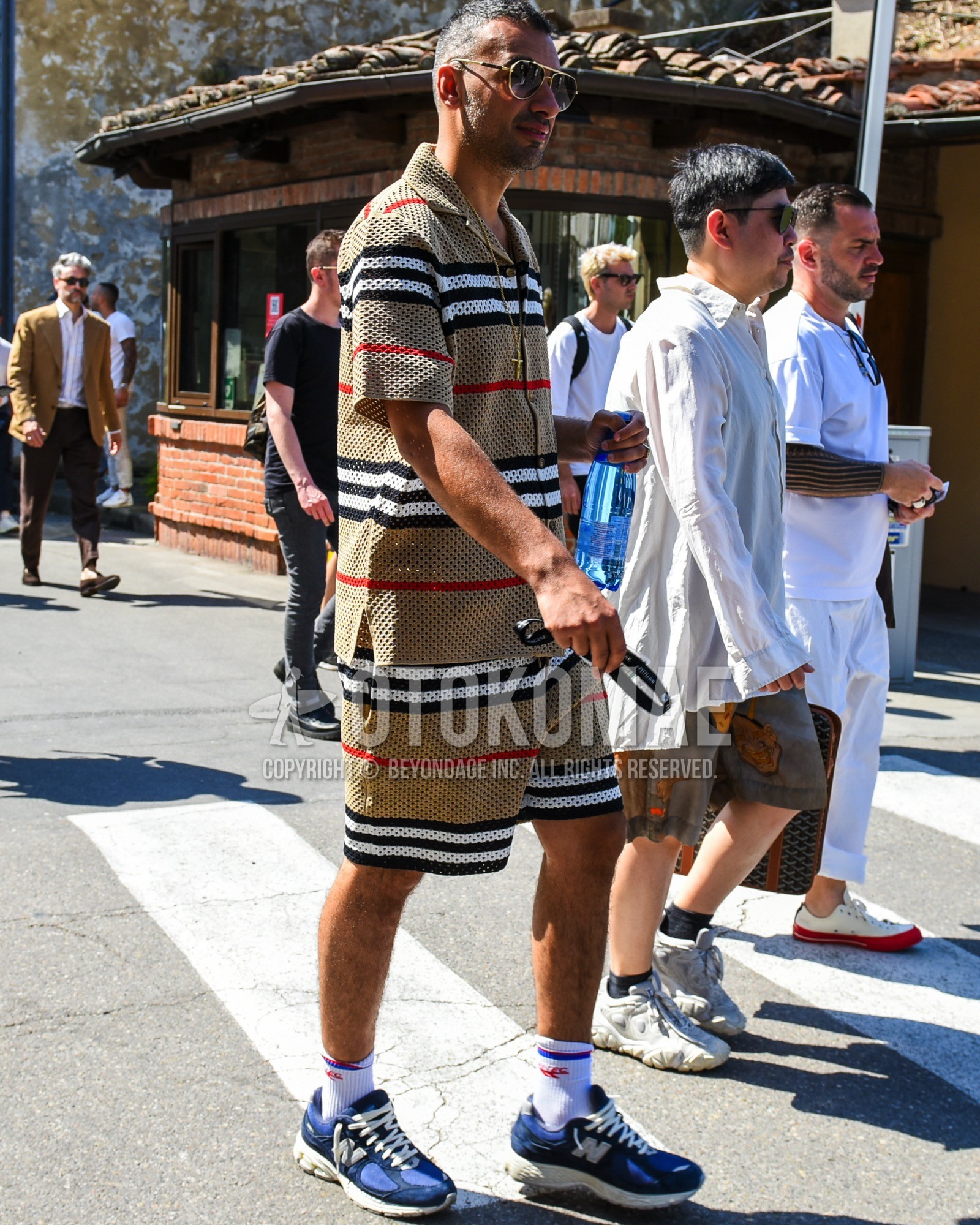 Men's spring summer outfit with gold plain sunglasses, white one point socks, navy blue low-cut sneakers, beige horizontal stripes casual setup.