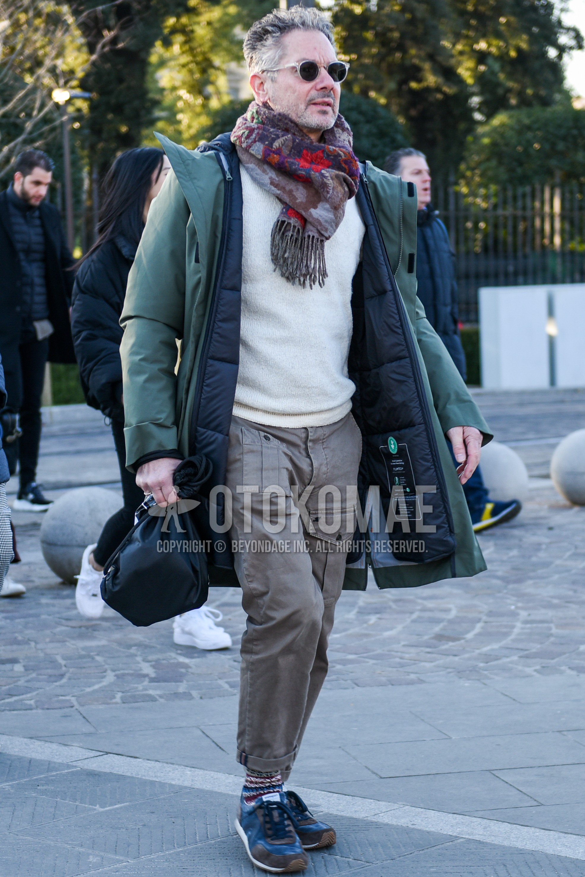 Men's winter outfit with clear plain sunglasses, multi-color scarf scarf, olive green plain down jacket, white plain sweater, beige plain cargo pants, multi-color socks socks, gray low-cut sneakers.