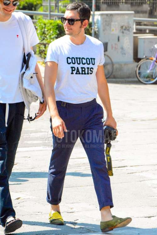 黒無地のサングラス、白グラフィックのTシャツ、グレー無地のスラックス、グレー無地のベルトレスパンツ、スエードのオリーブグリーンモンクシューズの革靴を合わせた春夏のメンズコーデ・着こなし。