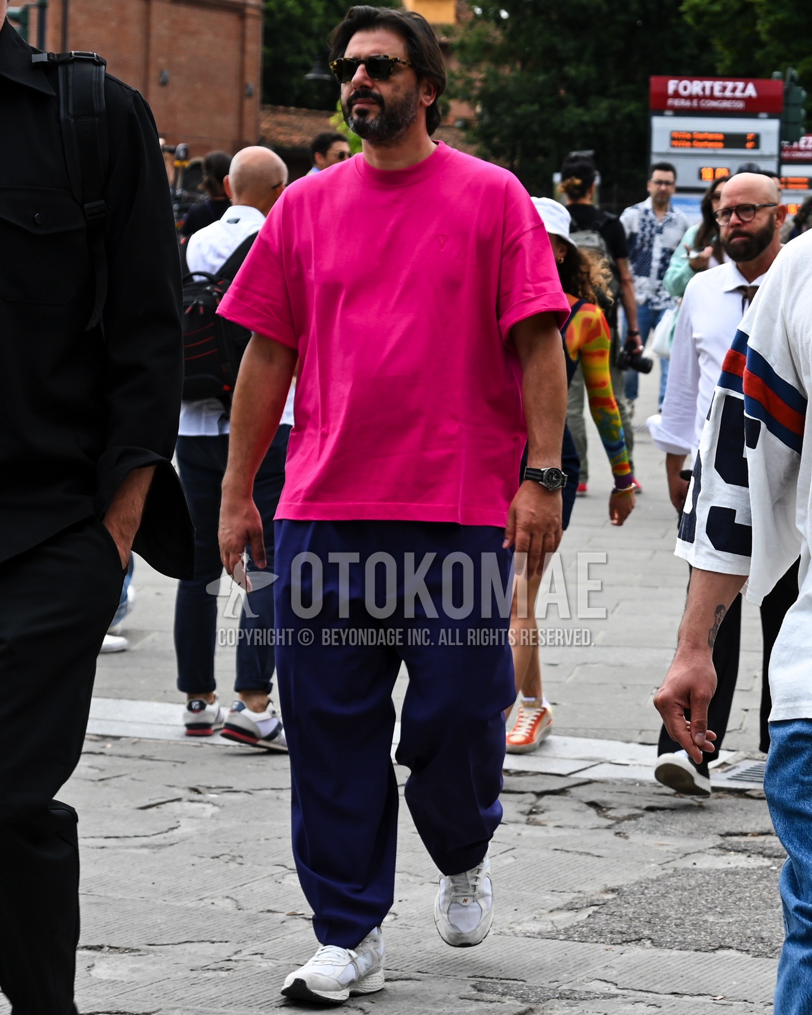 Men's spring summer outfit with black plain sunglasses, pink plain t-shirt, navy plain wide pants, white low-cut sneakers.