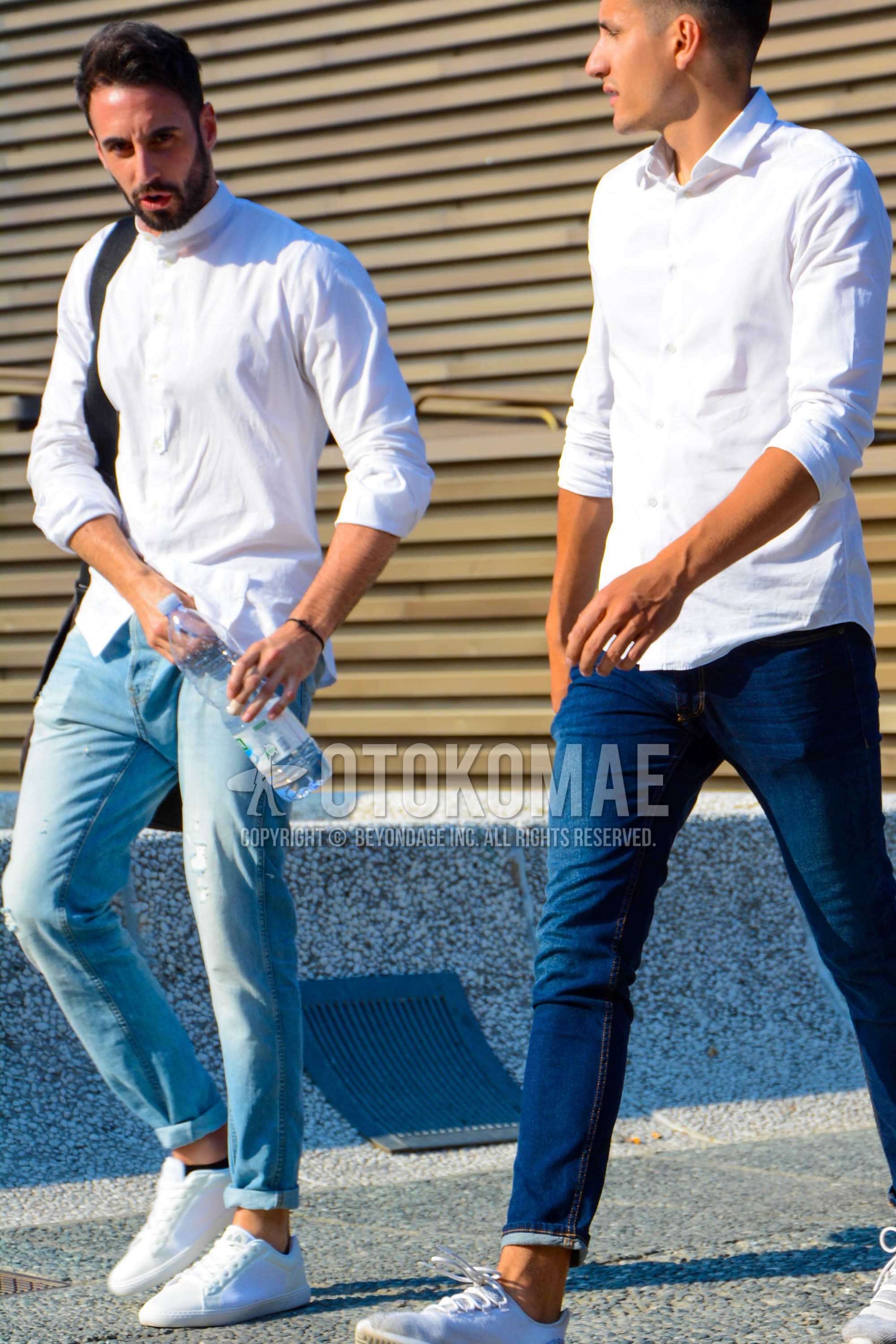Men's spring summer outfit with white plain shirt, light blue plain denim/jeans, white low-cut sneakers.