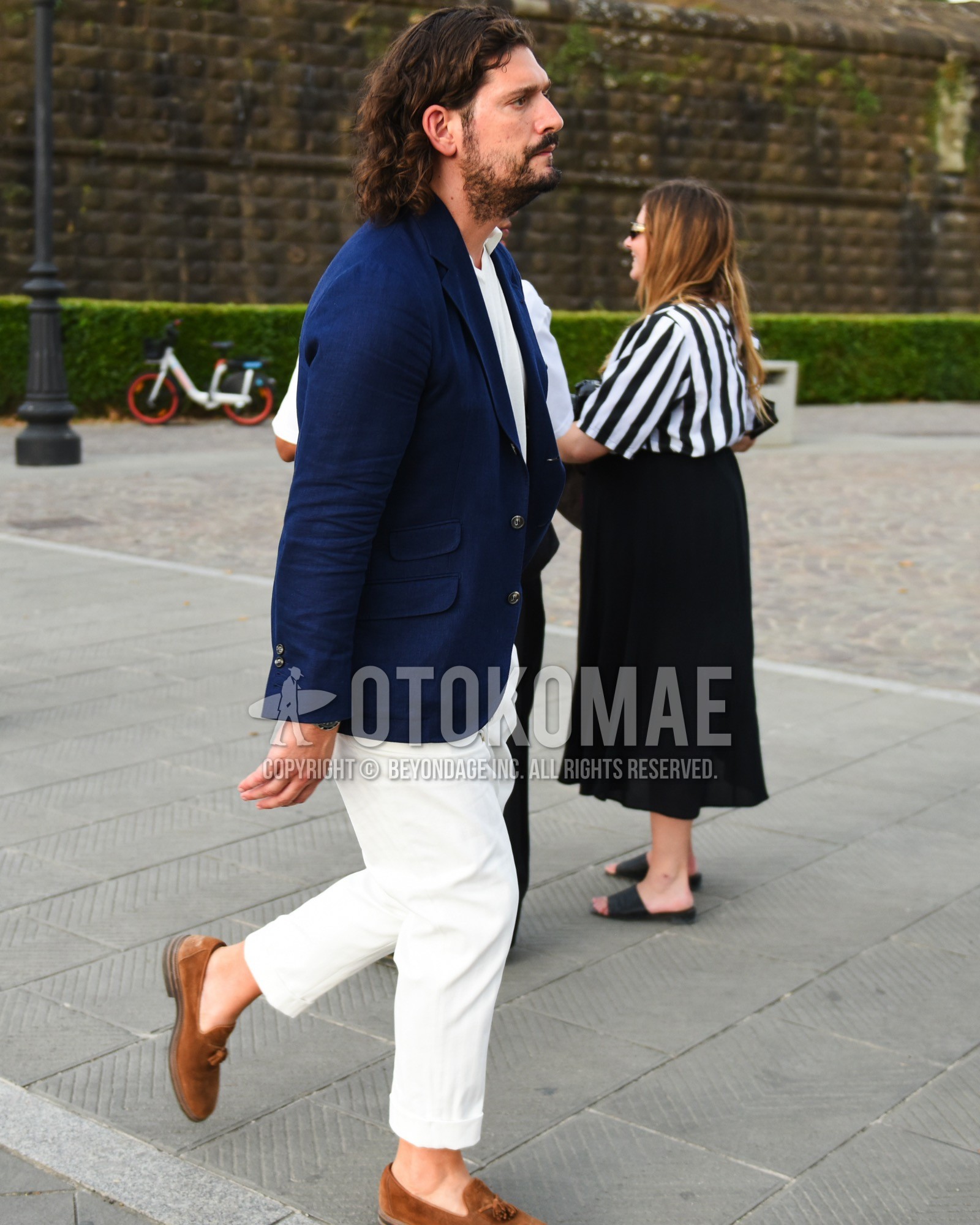 Men's spring summer outfit with navy plain tailored jacket, white plain t-shirt, white plain slacks, brown tassel loafers leather shoes.