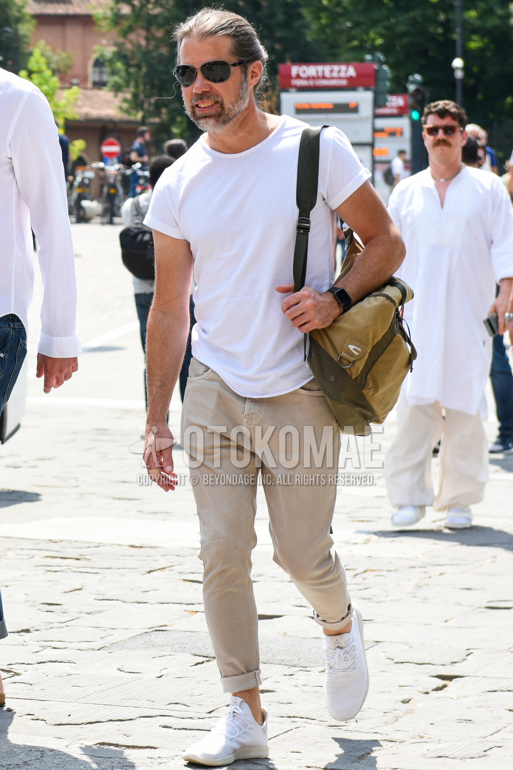 Men's summer outfit with silver plain sunglasses, white plain t-shirt, beige plain chinos, white low-cut sneakers, beige plain shoulder bag.