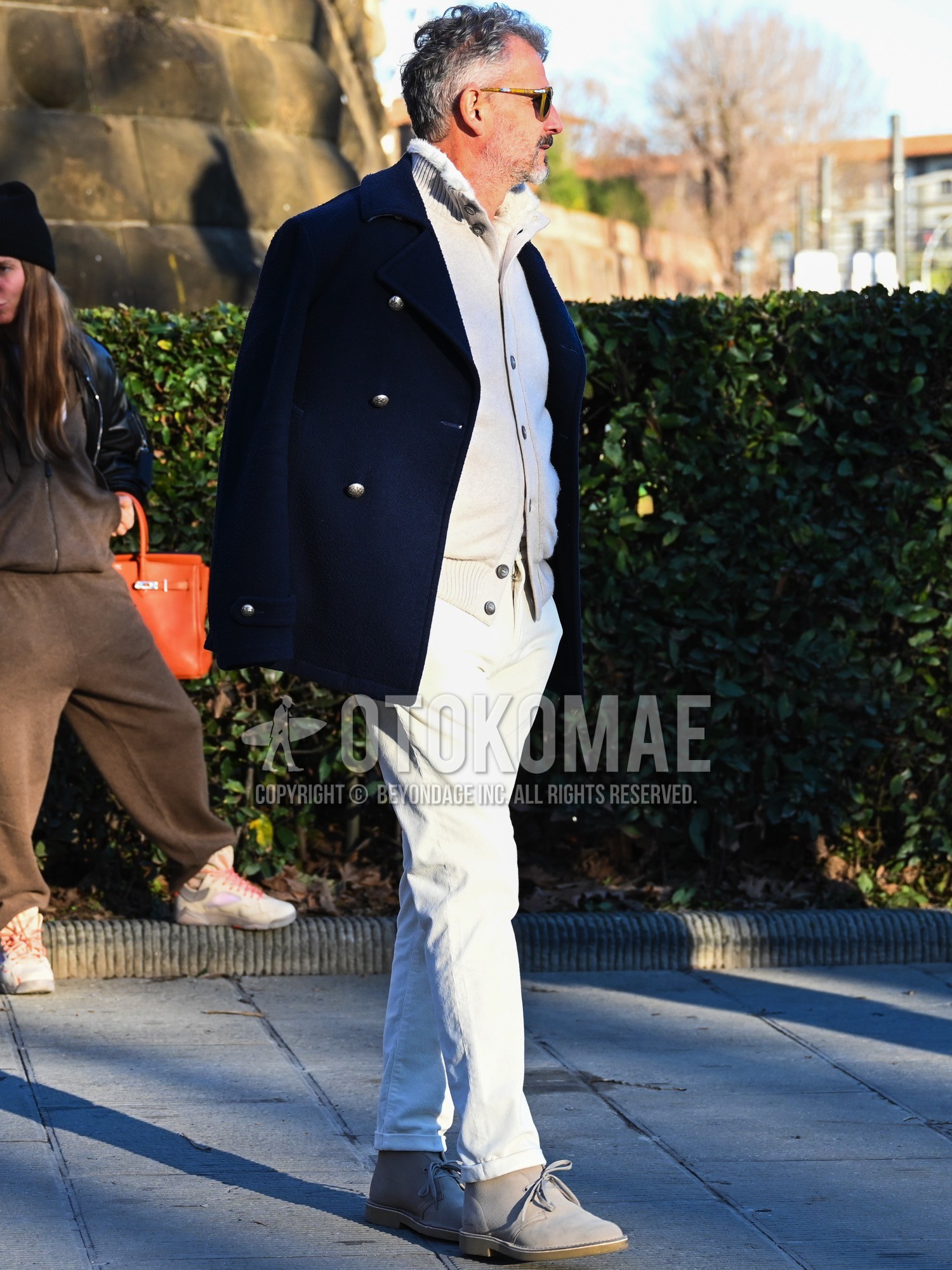 Men's autumn winter outfit with navy plain p coat, white plain cardigan, white plain chinos, beige chukka boots, beige  boots.