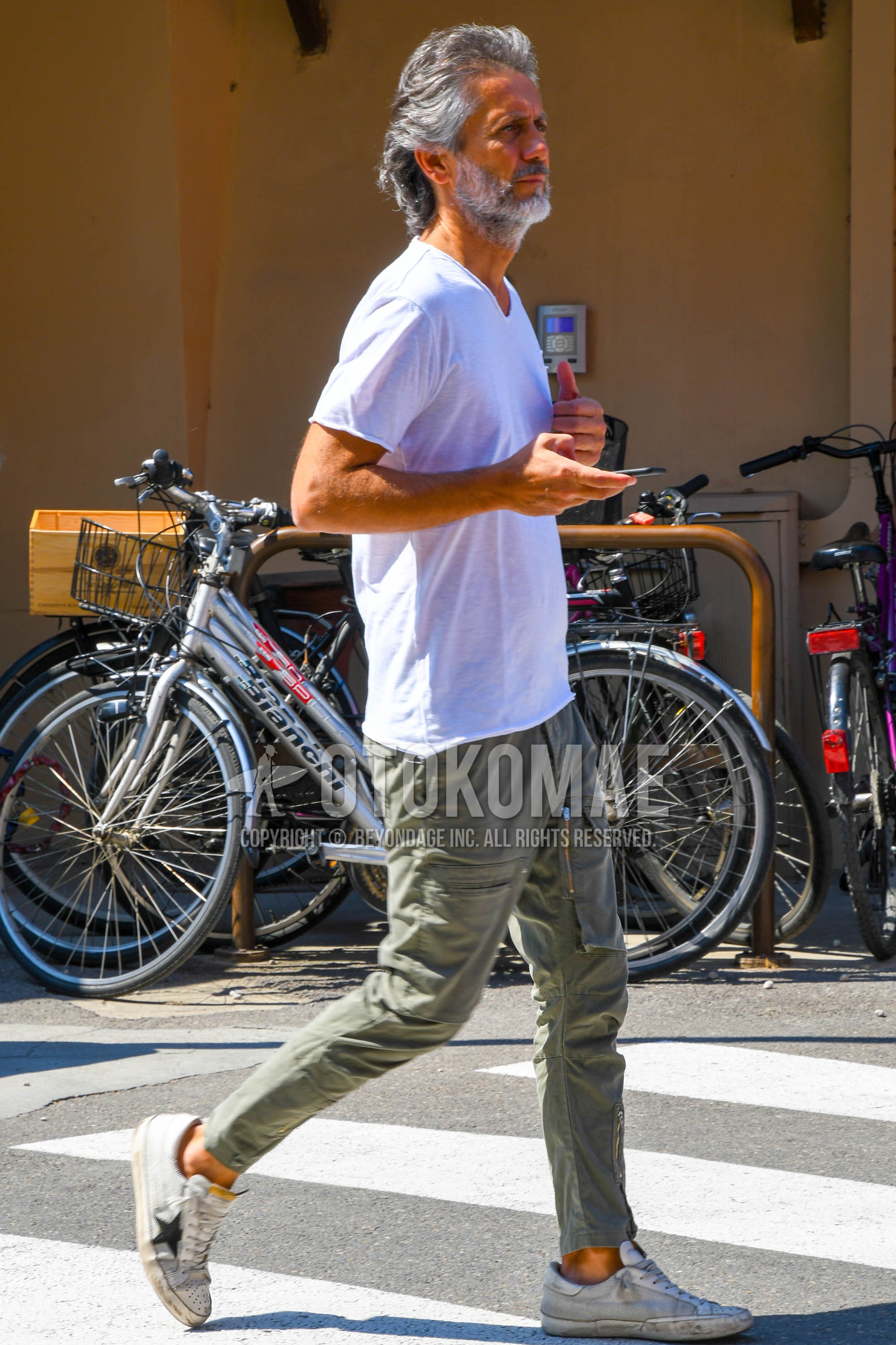 Men's summer outfit with white plain t-shirt, olive green plain cargo pants, white low-cut sneakers.