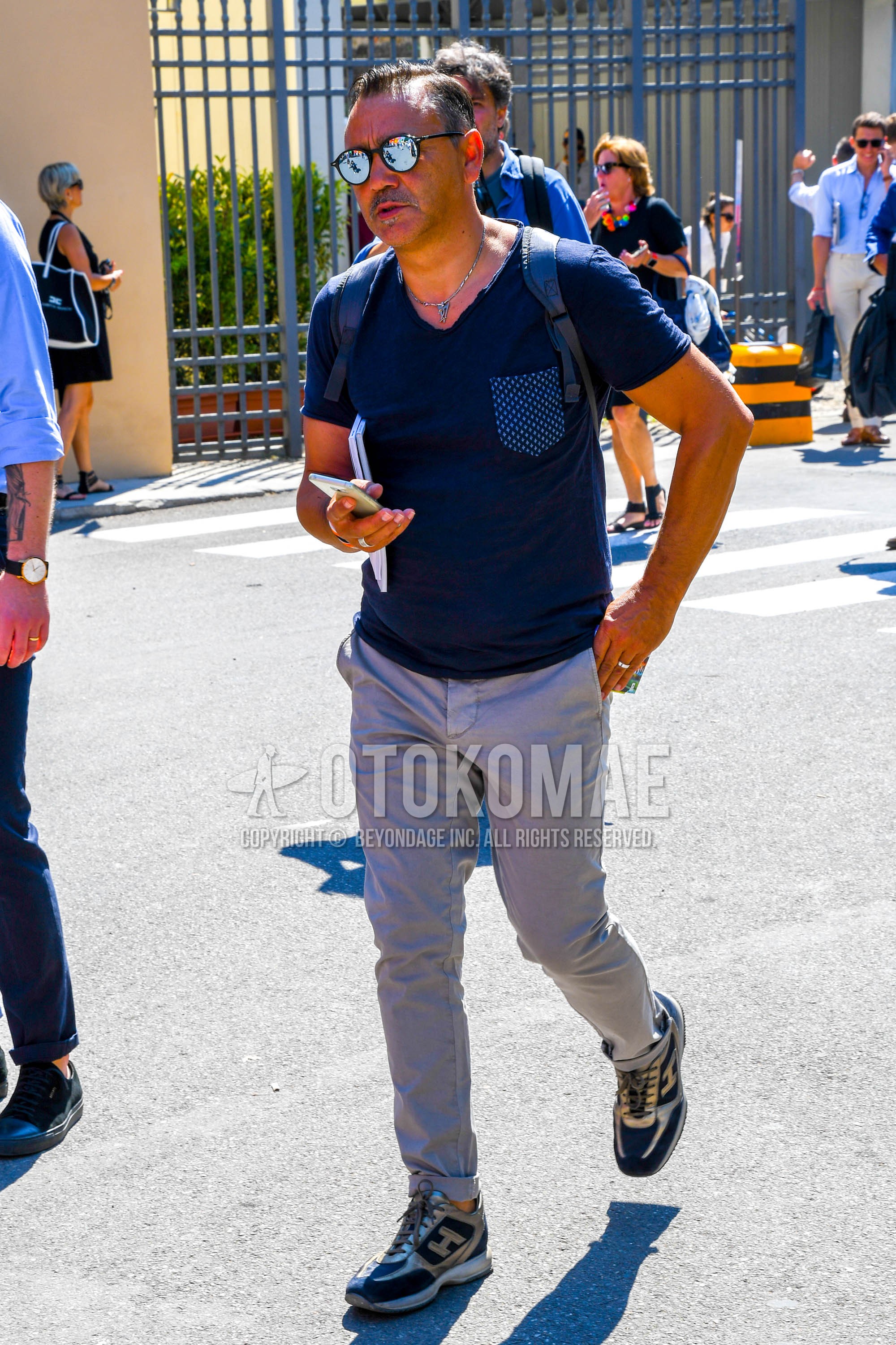 Men's summer outfit with plain sunglasses, navy plain t-shirt, gray plain chinos, navy low-cut sneakers.
