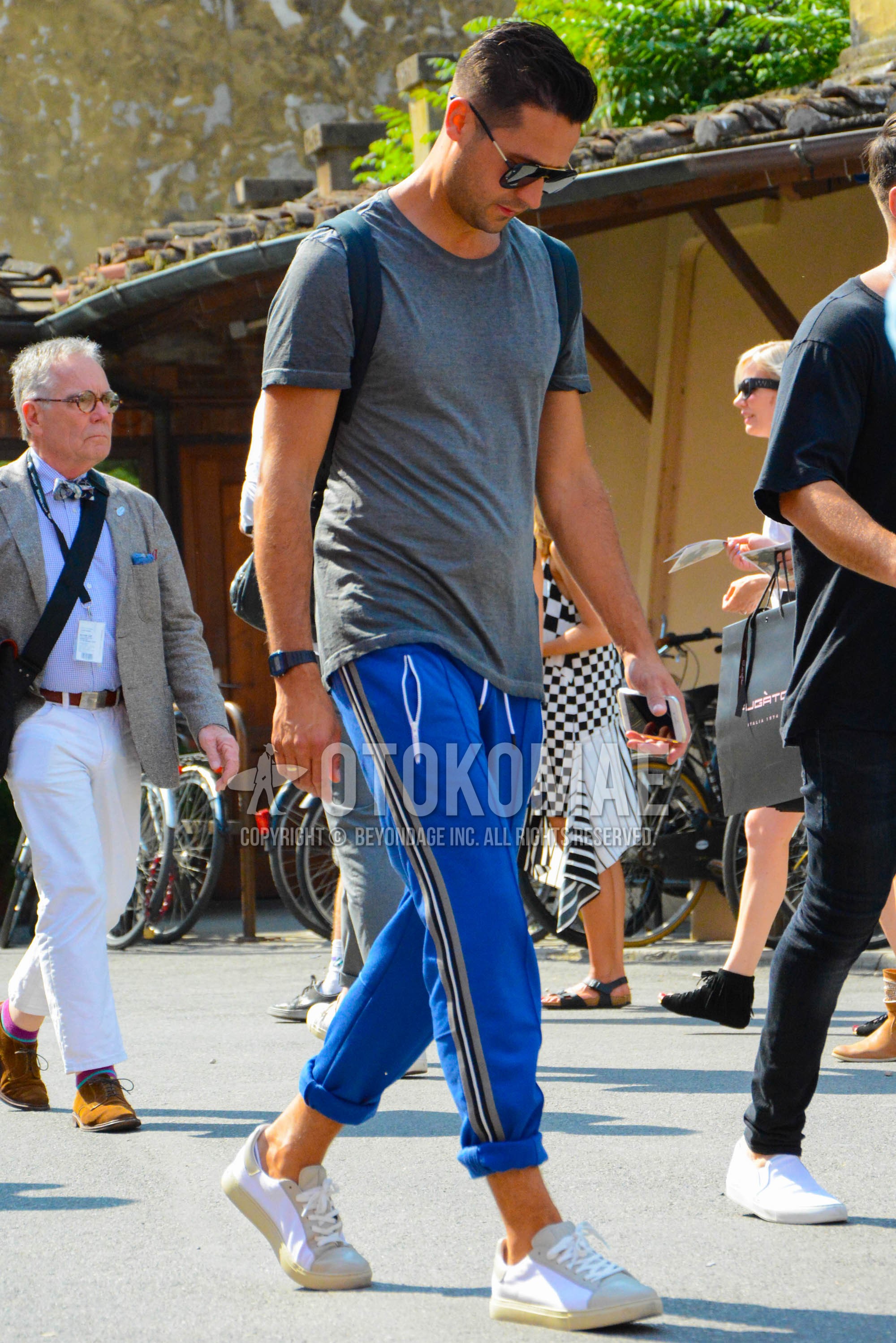 Men's summer outfit with plain sunglasses, dark gray plain t-shirt, blue plain sideline pants, blue plain easy pants, white low-cut sneakers.