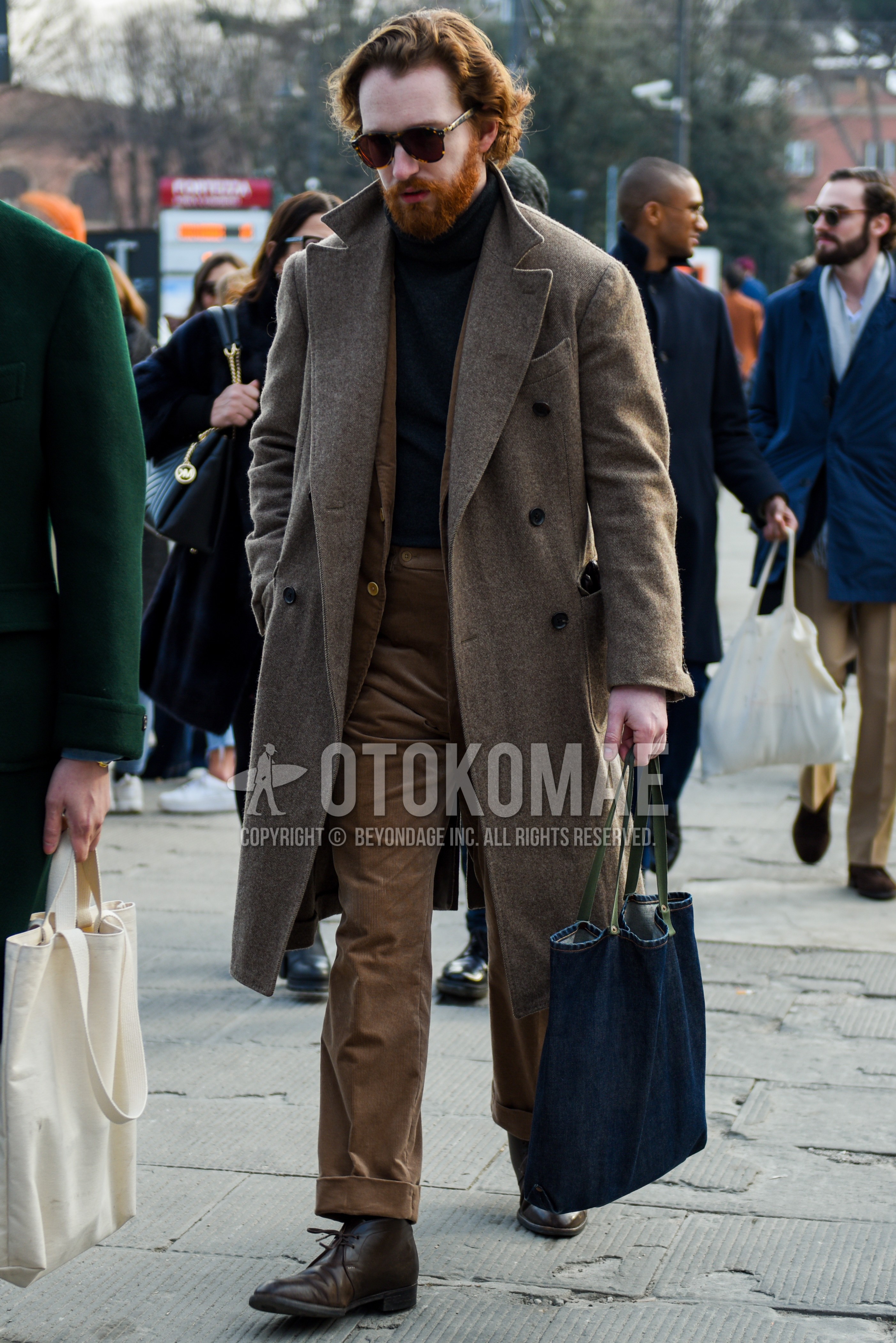 Men's autumn winter outfit with brown tortoiseshell sunglasses, beige plain chester coat, gray plain turtleneck knit, brown chukka boots, blue plain tote bag, beige plain suit.