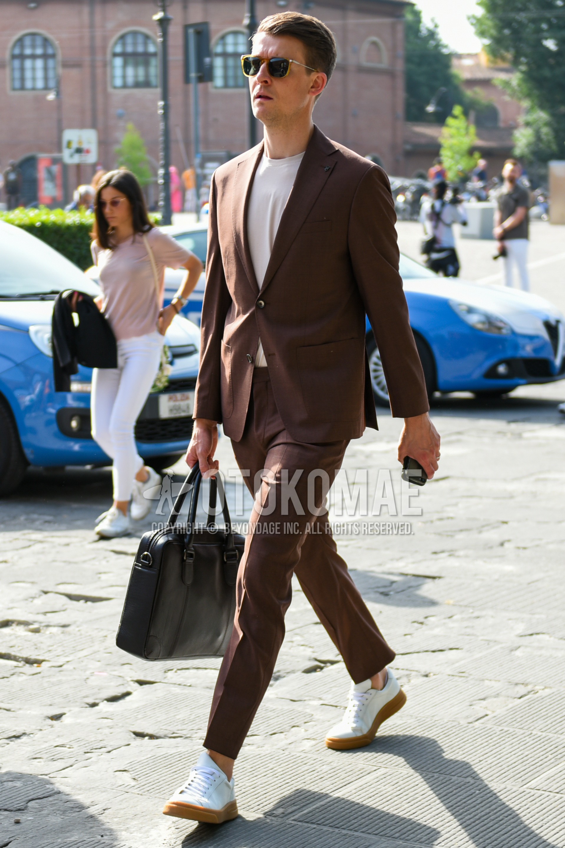 Men's spring summer autumn outfit with plain sunglasses, white plain t-shirt, white sneakers, black plain briefcase/handbag, brown plain suit.