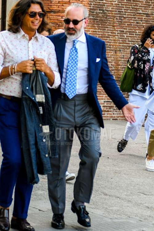 無地のサングラス、ネイビー無地のテーラードジャケット、白無地のシャツ、グレー無地のベルトレスパンツ、無地のスラックス、グレー無地のソックス、黒タッセルローファーの革靴、水色ネクタイのネクタイを合わせた春夏秋のメンズコーデ・着こなし。