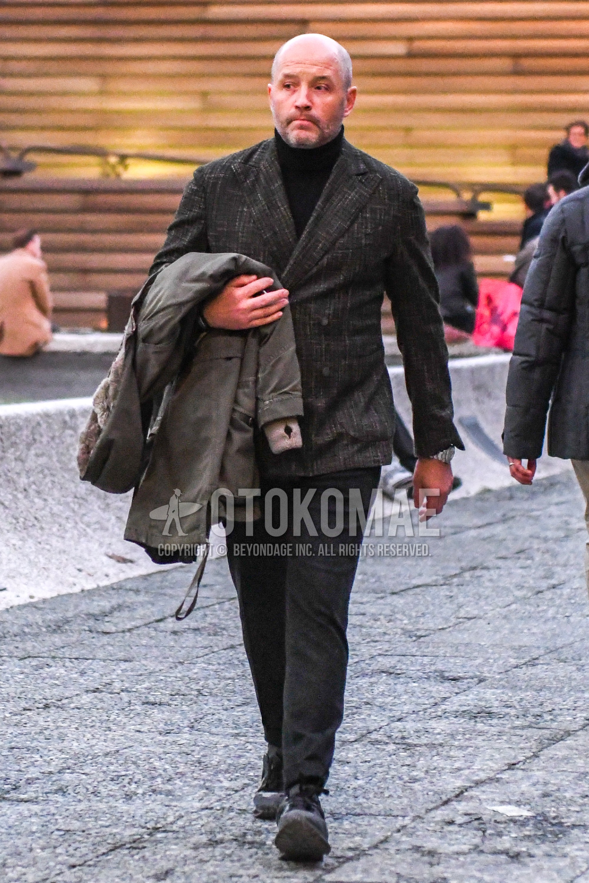 Men's autumn winter outfit with brown check tailored jacket, black plain turtleneck knit, dark gray plain slacks, black low-cut sneakers.
