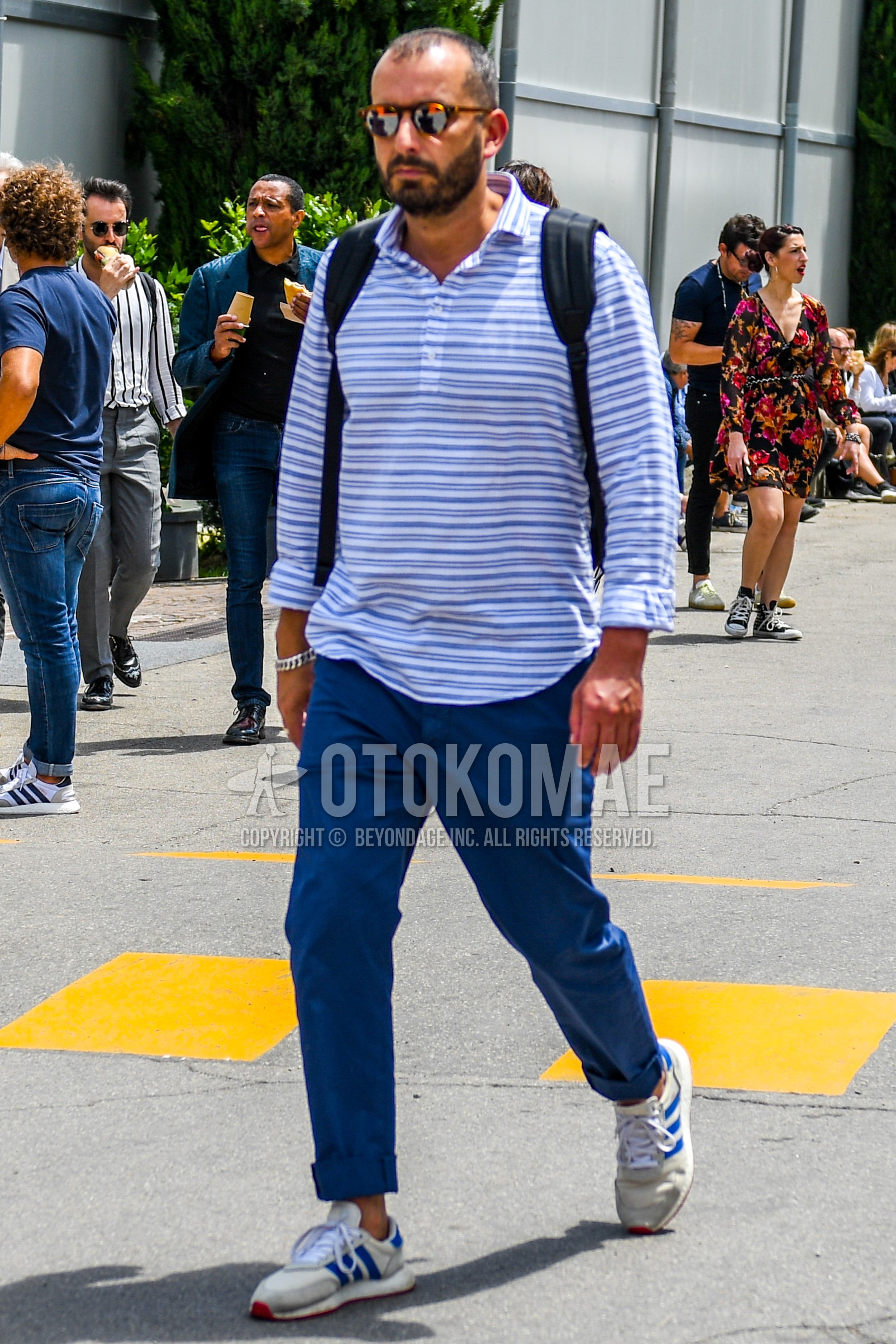 Men's spring summer outfit with tortoiseshell sunglasses, white blue horizontal stripes shirt, blue plain cotton pants, white low-cut sneakers.
