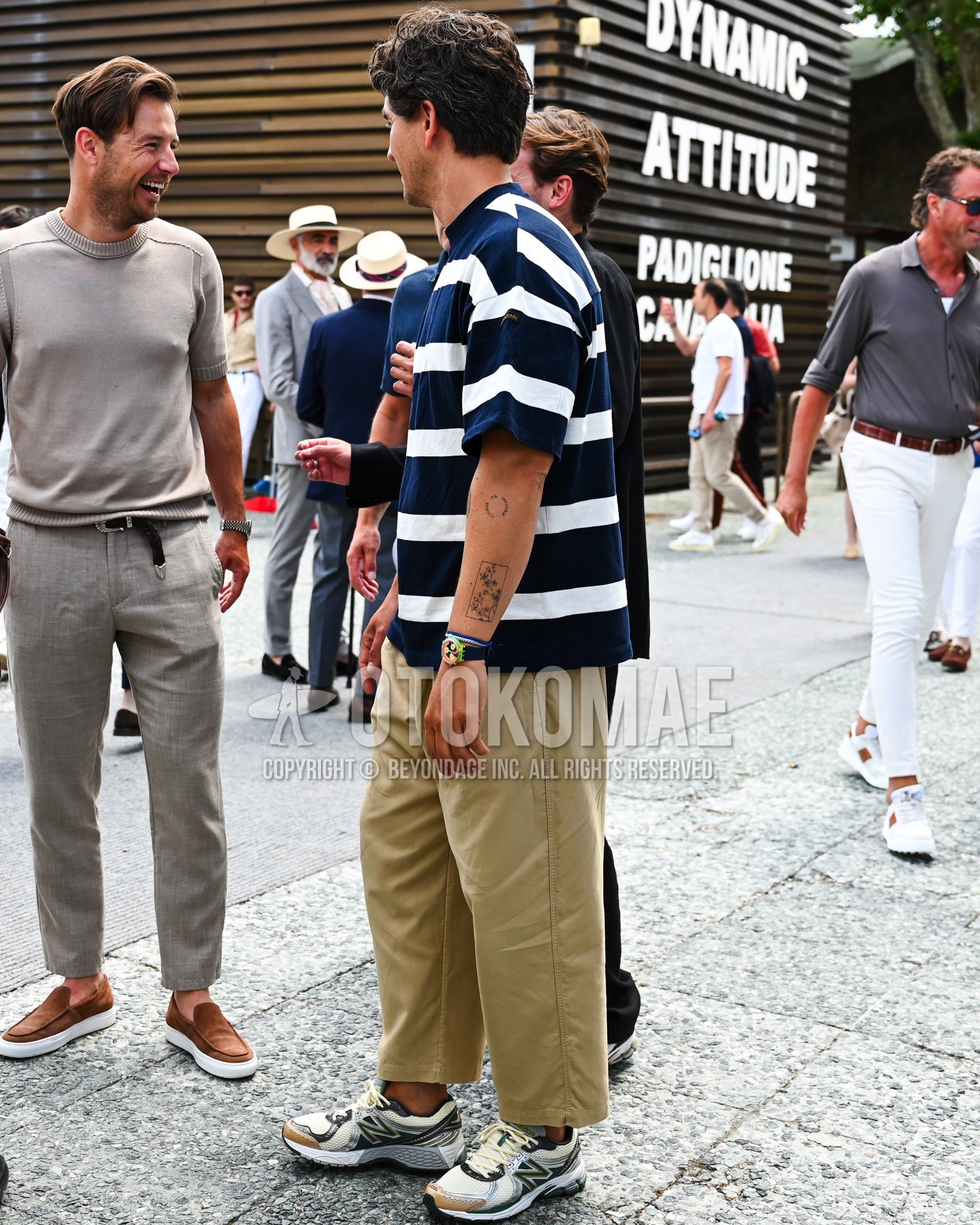 Men's spring summer outfit with navy plain t-shirt, beige plain chinos, white low-cut sneakers.