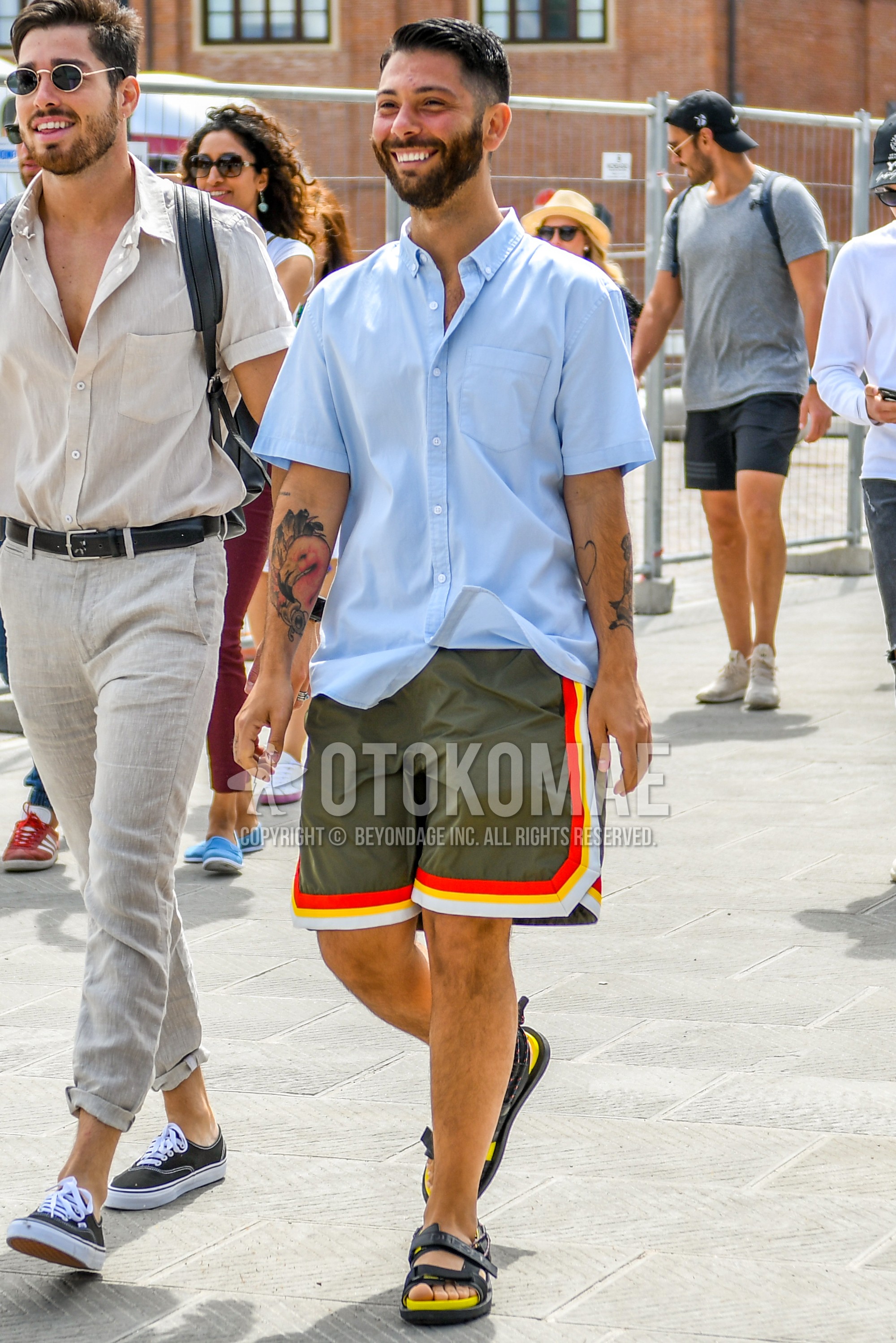 Men's summer outfit with light blue plain shirt, olive green plain short pants, yellow black sport sandals.
