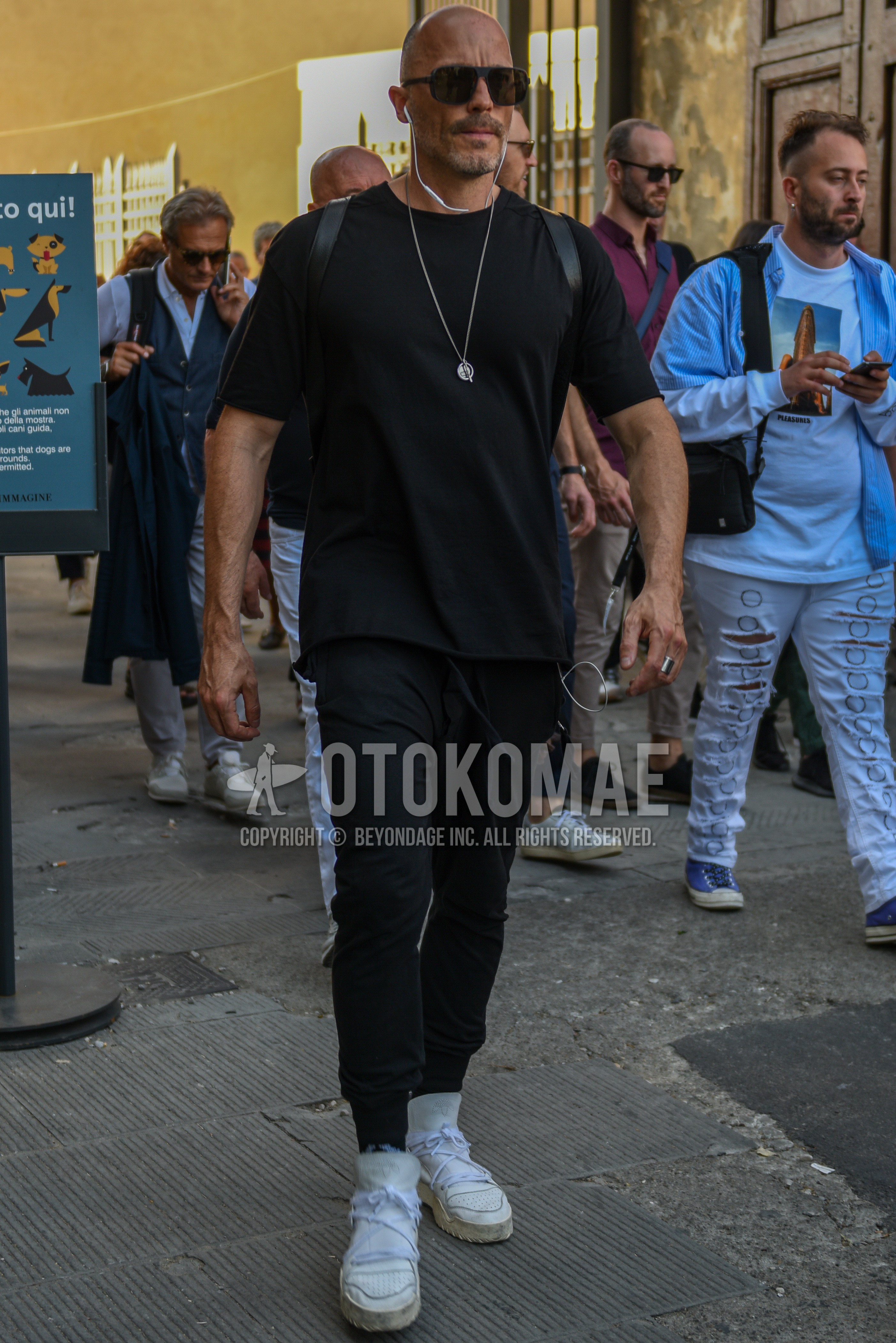 Men's summer outfit with black plain sunglasses, black plain t-shirt, black plain sweatpants, plain sideline pants, white low-cut sneakers.