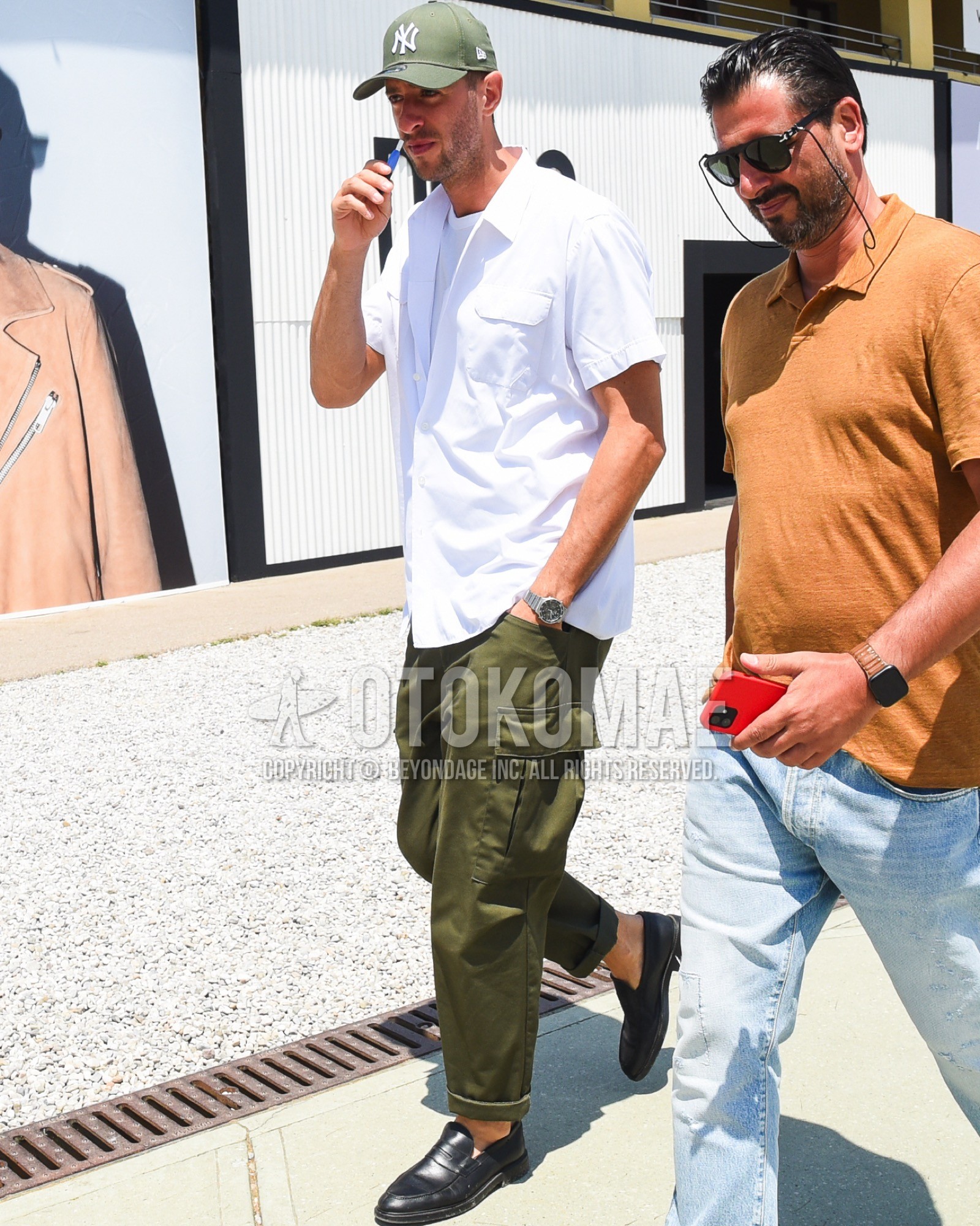 Men's spring summer outfit with olive green deca logo baseball cap, white plain shirt, white plain t-shirt, olive green plain cargo pants, black coin loafers leather shoes.