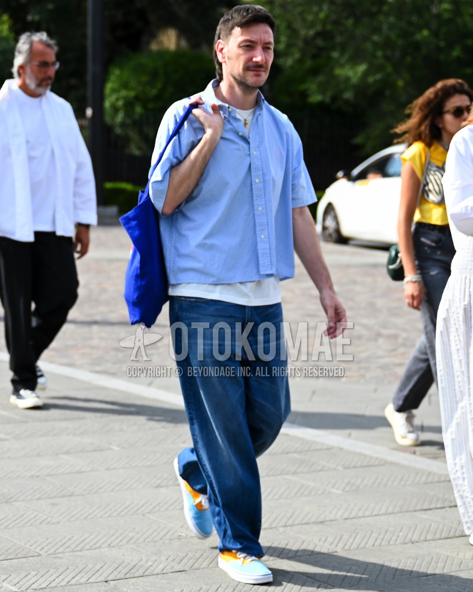 Men's spring summer autumn outfit with light blue plain shirt, white plain t-shirt, blue plain denim/jeans, light blue low-cut sneakers, blue plain tote bag.